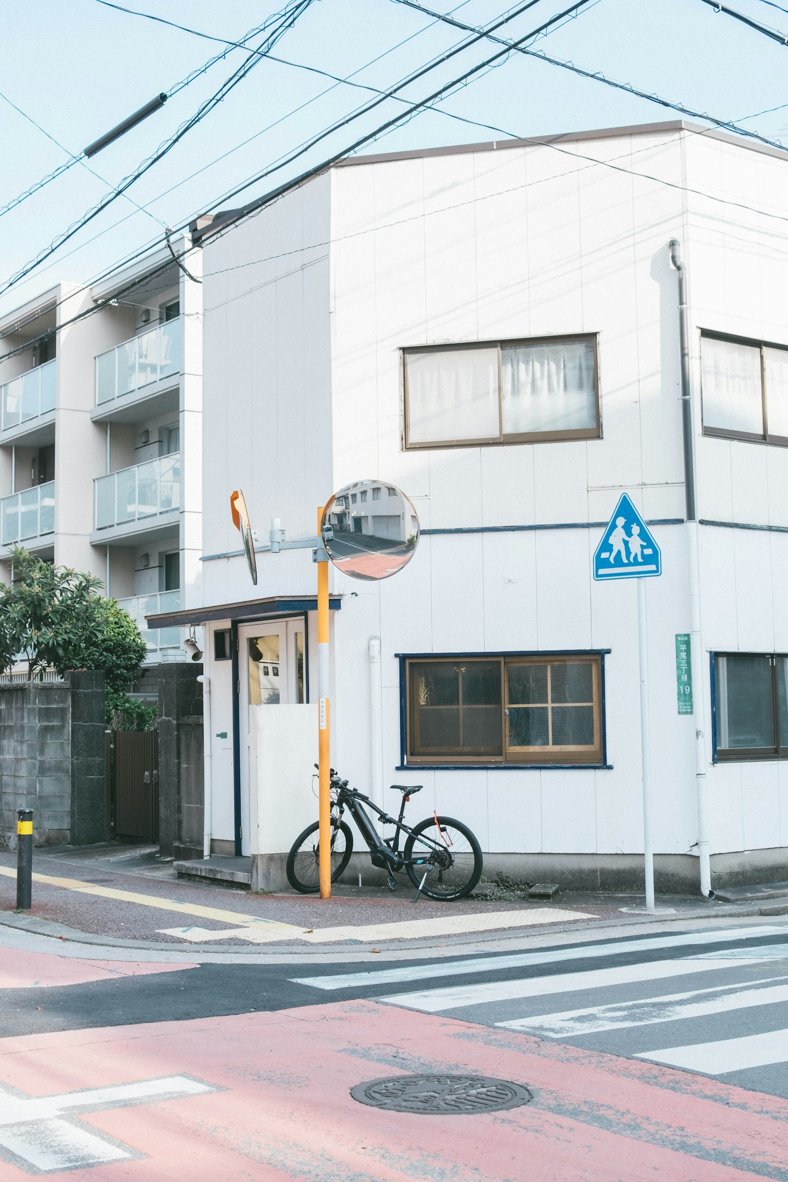 Street view featuring a white building and bicycle at an intersection