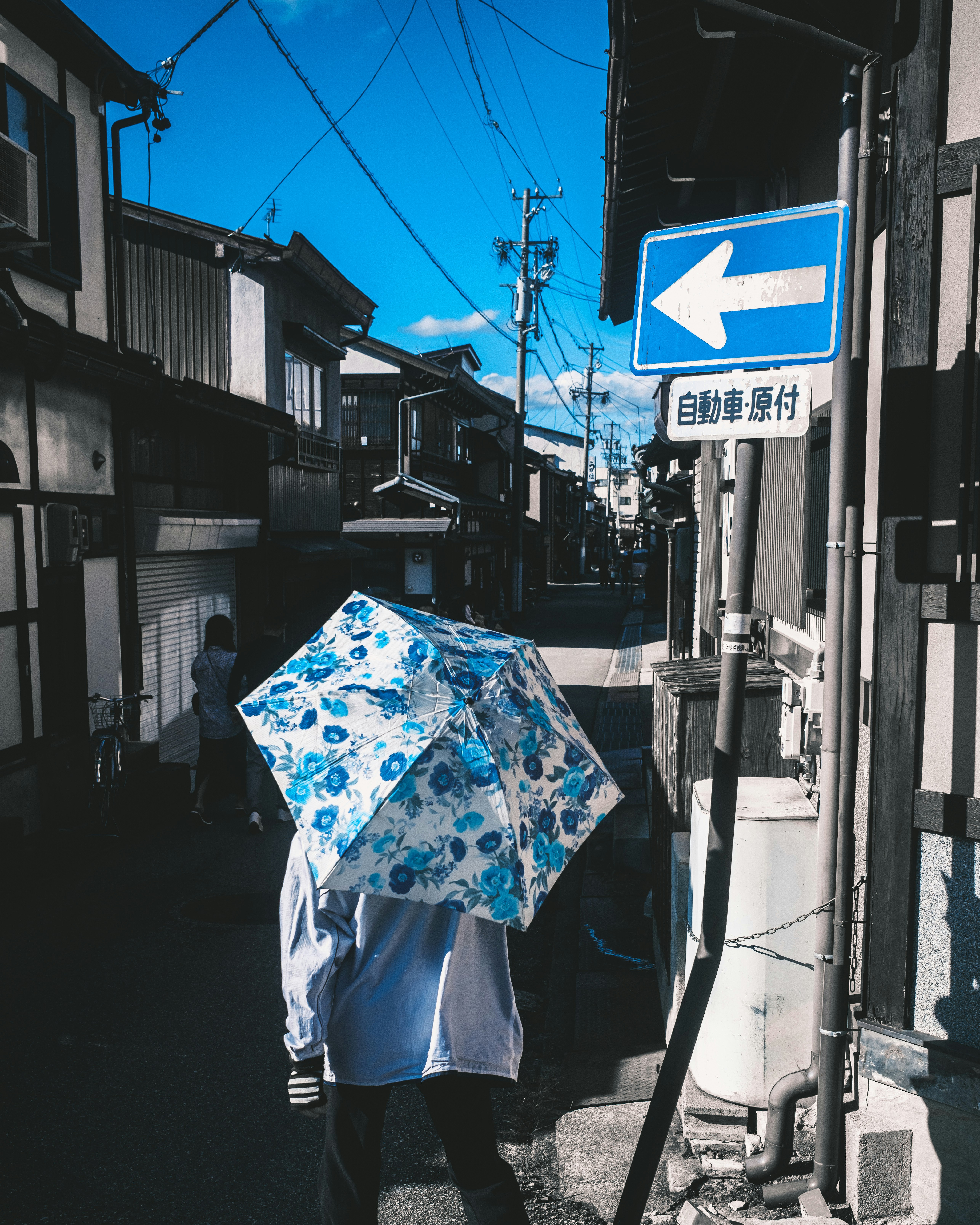藍天下帶藍色雨傘的商店街巷弄