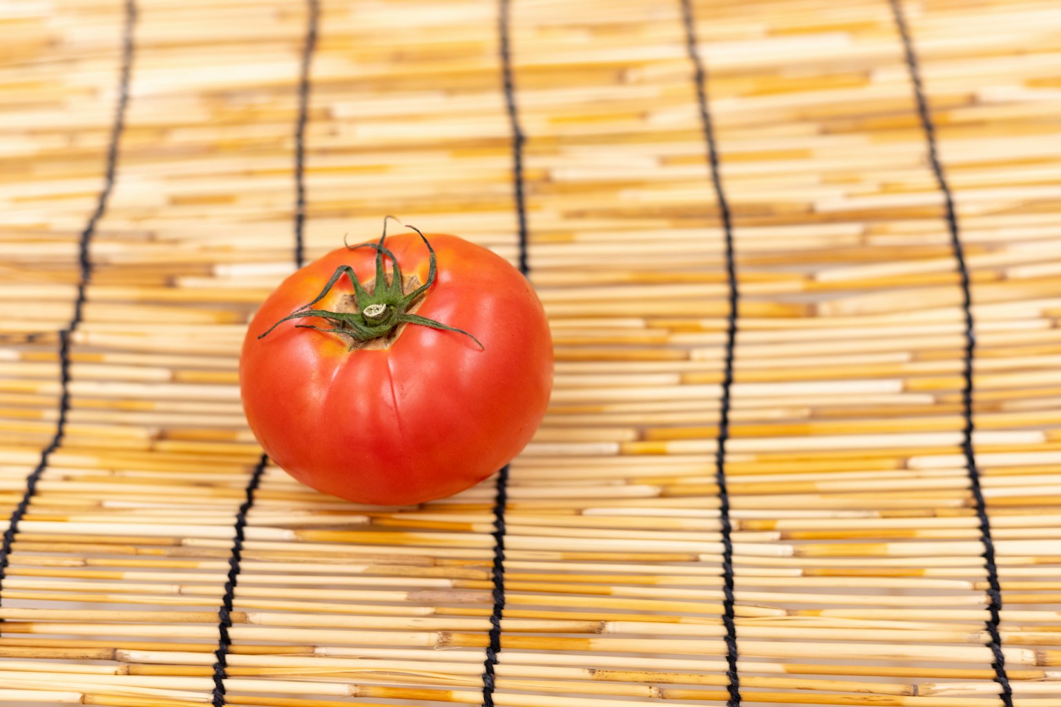 Eine rote Tomate auf einer Bambusmatte