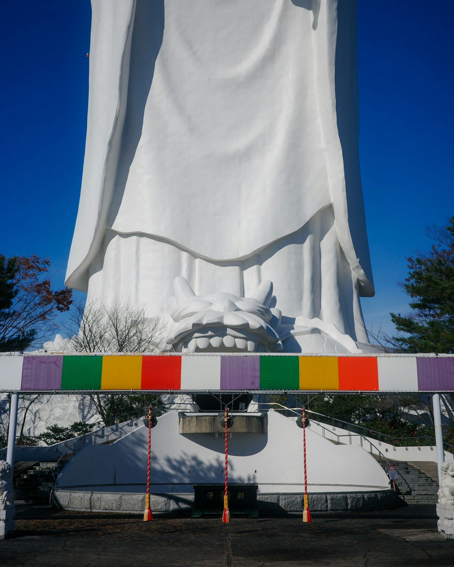Große weiße Statue mit bunten Dekorationen darunter und blauem Himmel