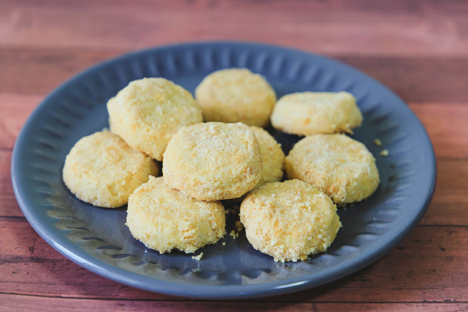 Kroket kuning yang dilapisi roti disusun di piring biru