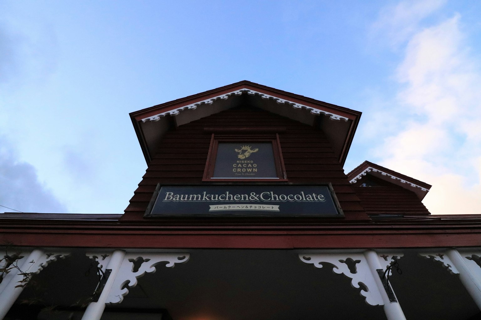 Vue extérieure d'un bâtiment en bois avec une enseigne pour Baumkuchen et Chocolat