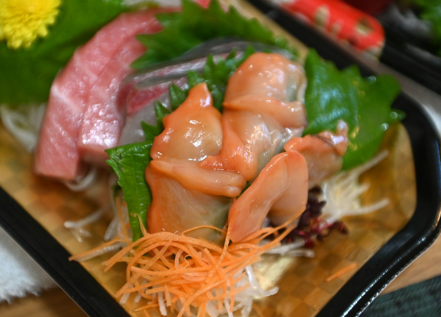 Fresh sashimi platter with vibrant green leafy vegetables
