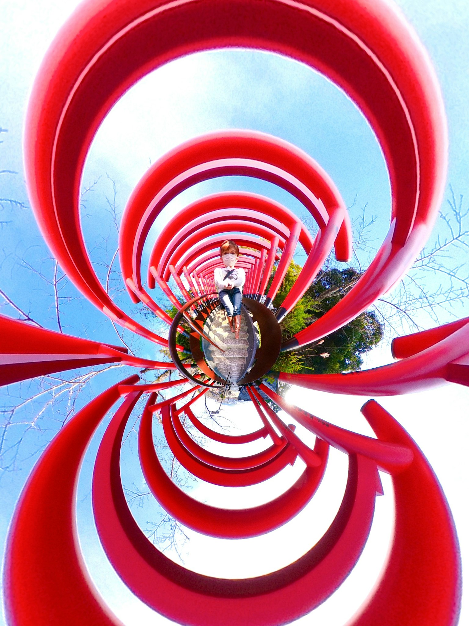 Escultura circular roja que se espiraliza hacia el cielo