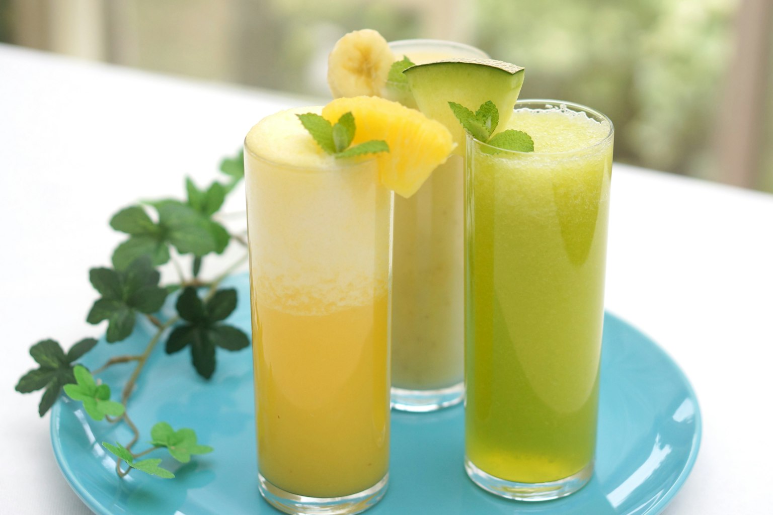 Verres de jus colorés disposés sur une assiette bleue