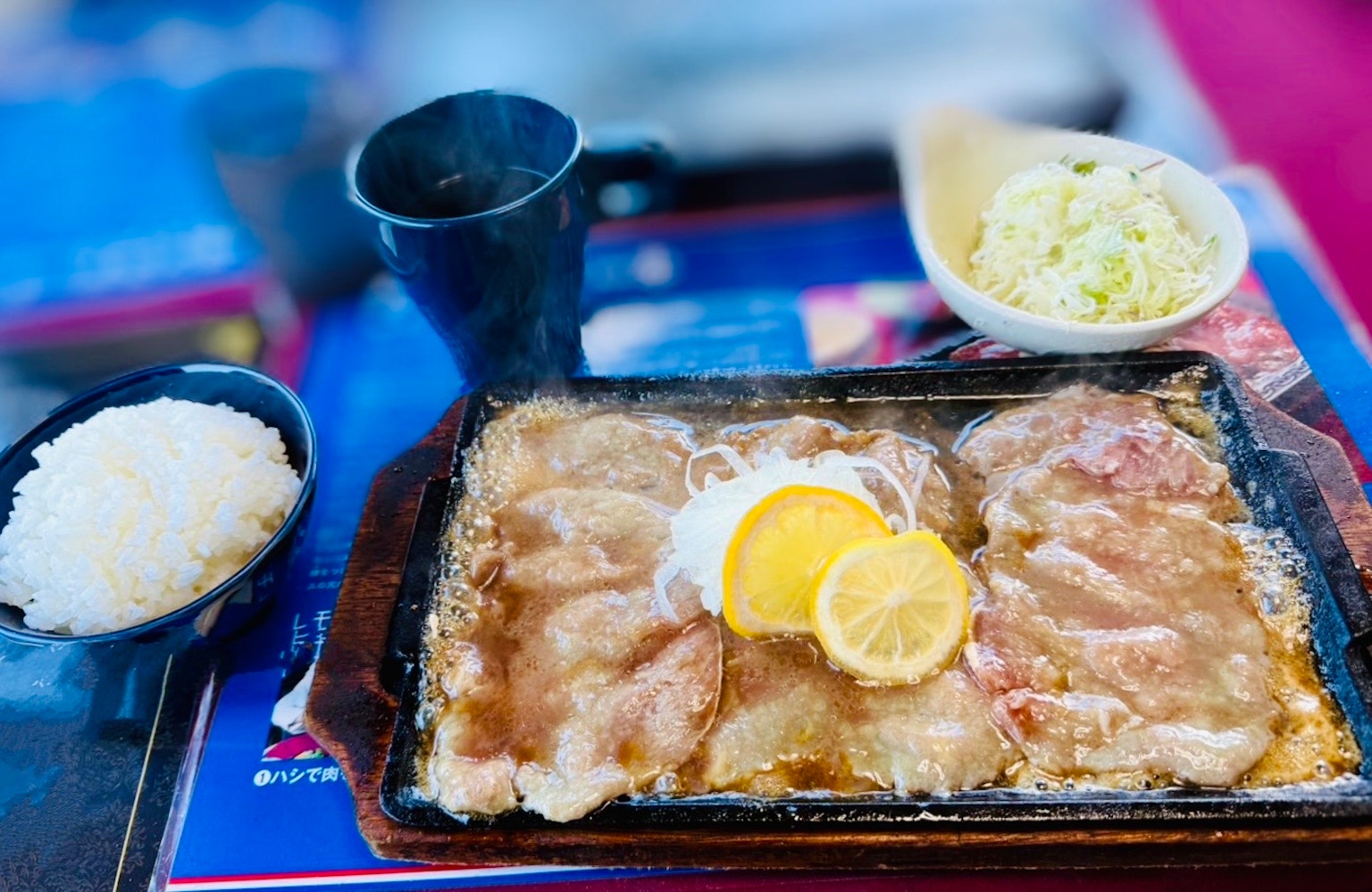 热烤猪肉配柠檬，旁边有米饭和卷心菜