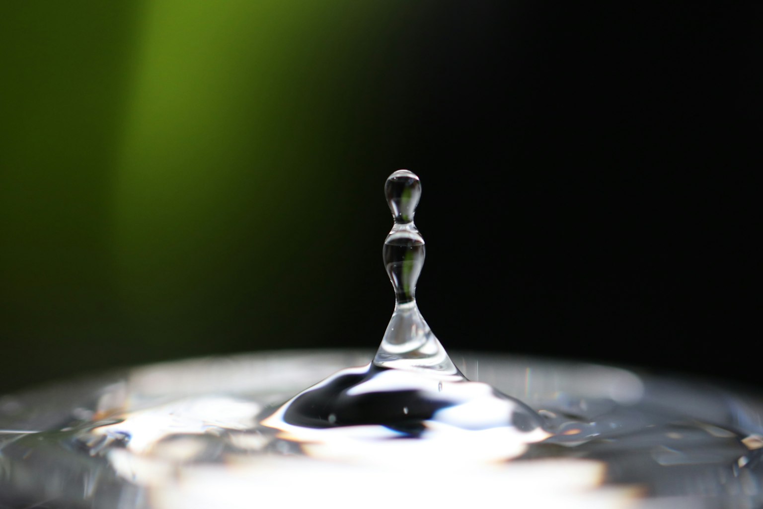 Gros plan d'une goutte d'eau surface brillante avec un fond vert