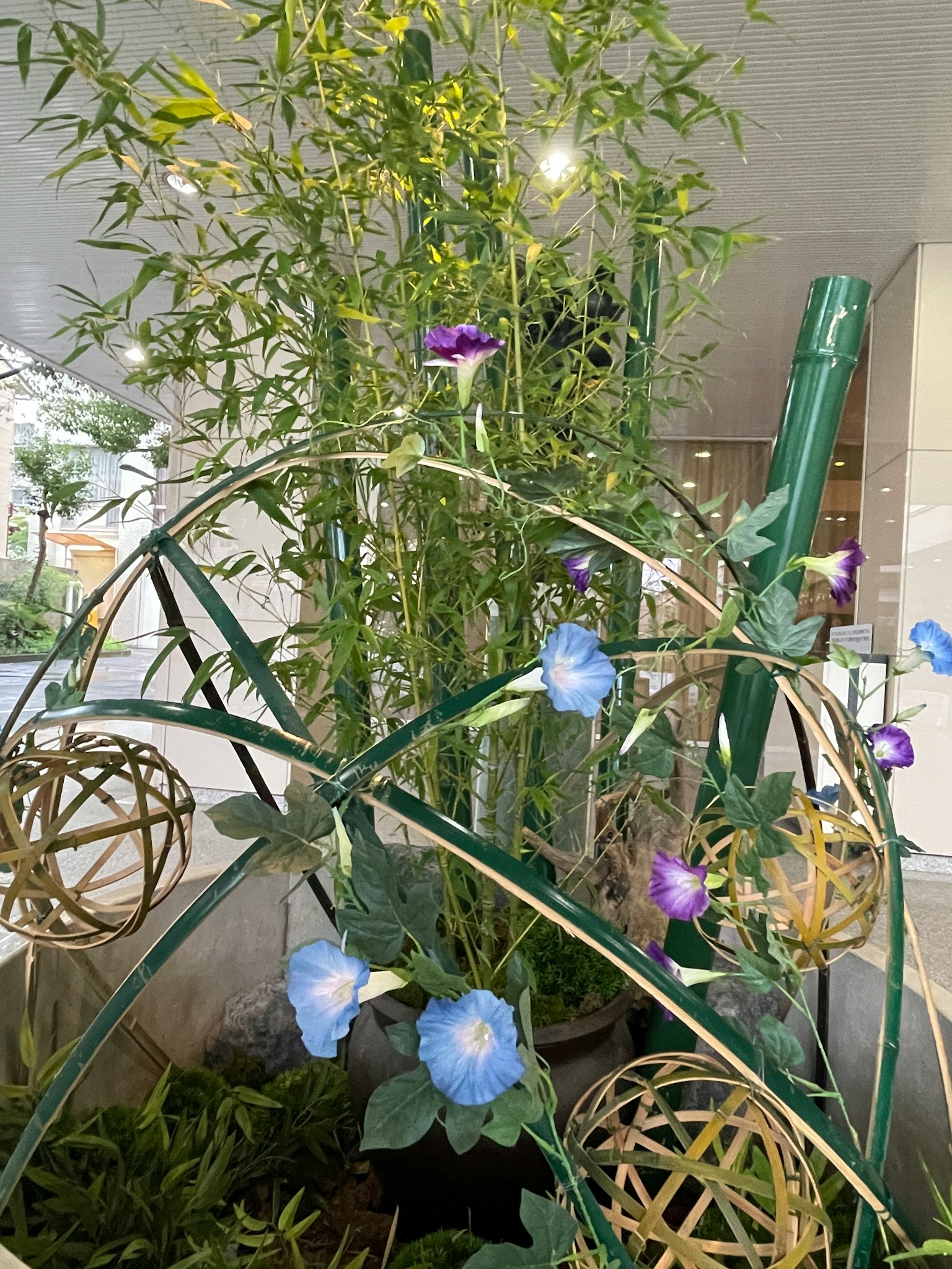 Arrangement of blue and purple flowers with bamboo decor and golden spheres