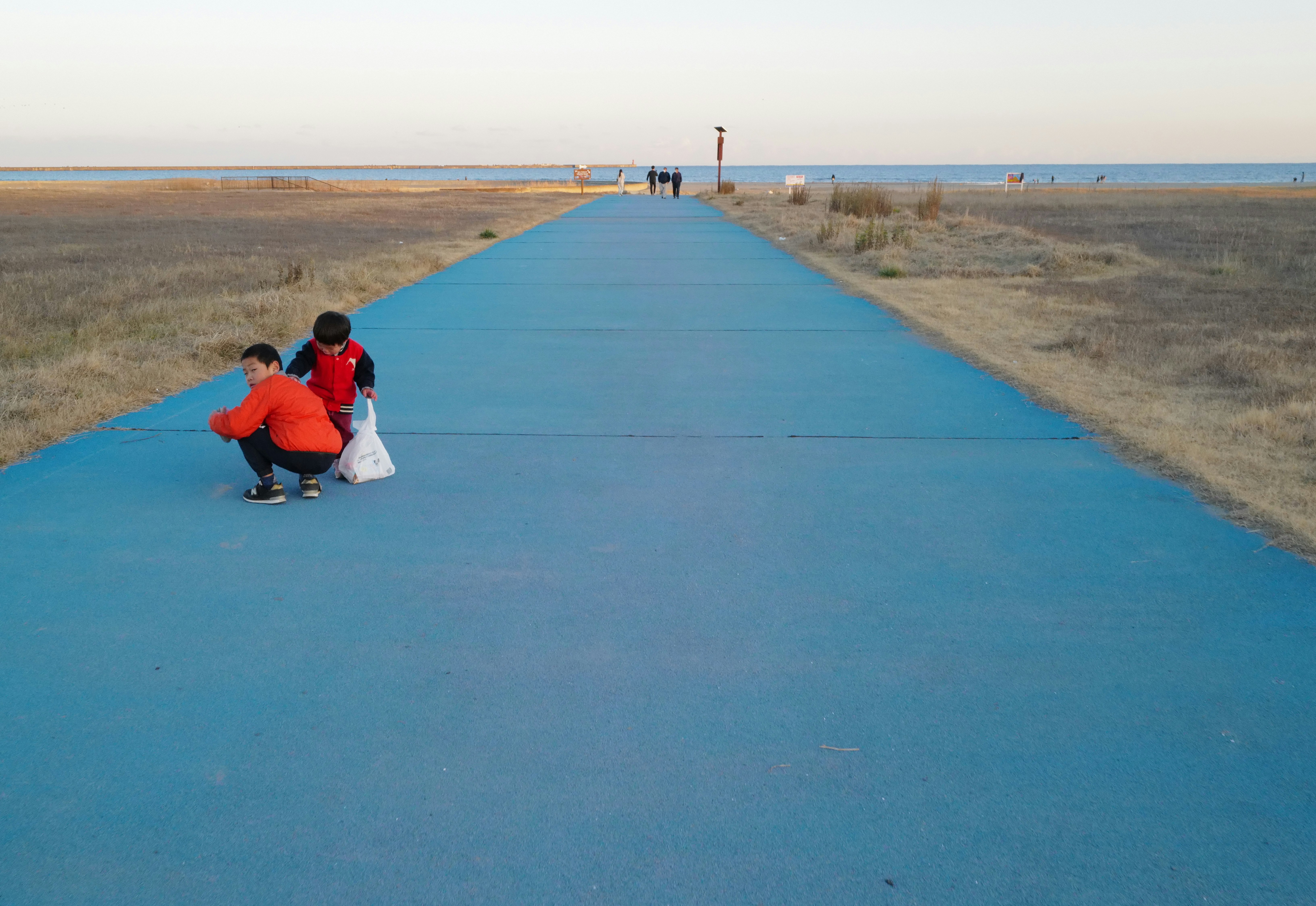 persone sedute su una passerella costiera blu con un lungo rettilineo