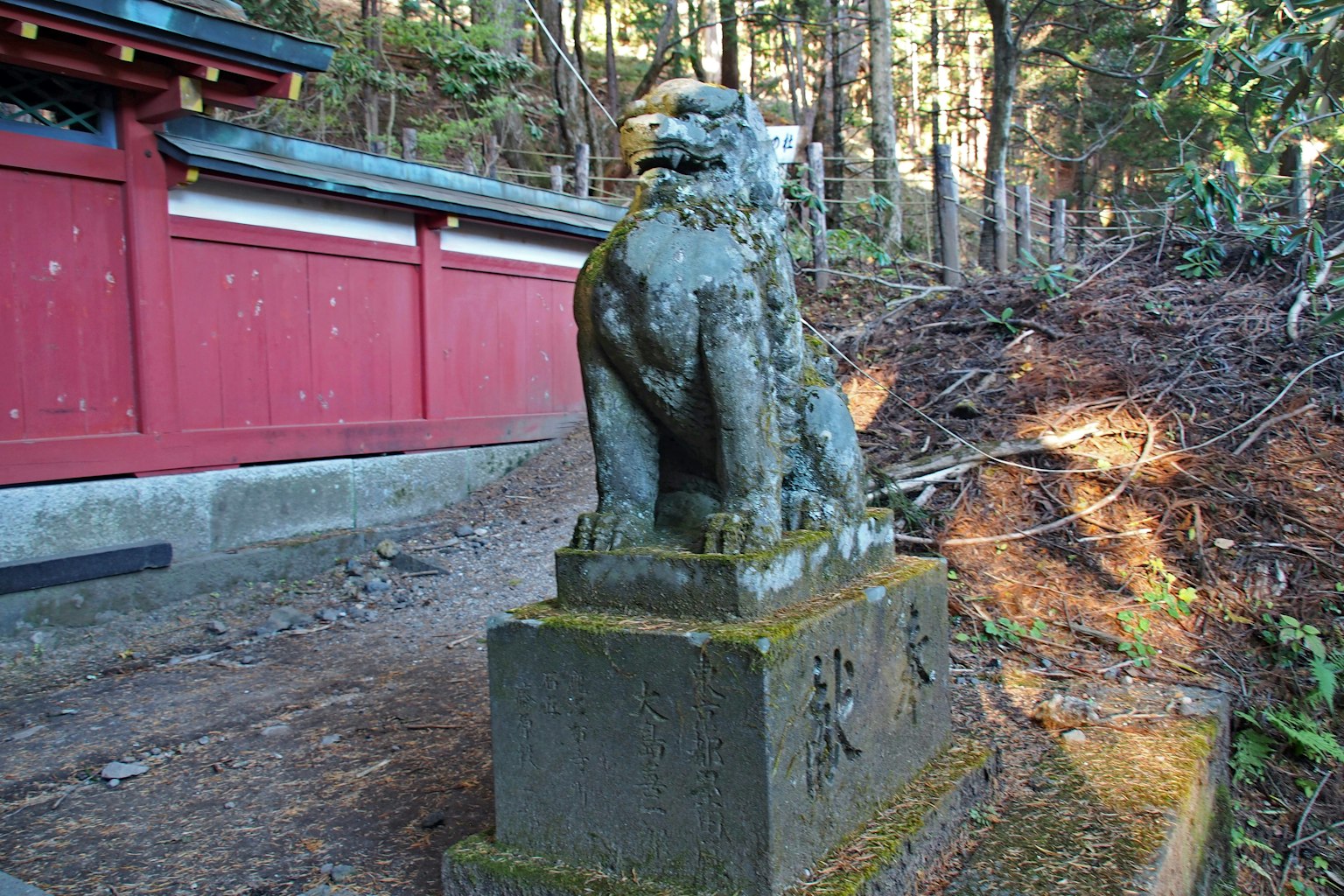 Statue de lion couverte de mousse près d'un mur rouge