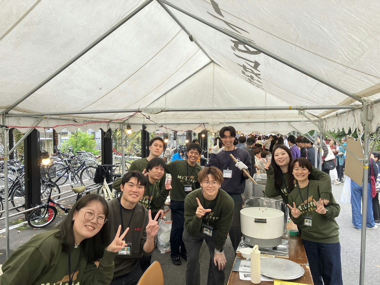 Smiling staff giving peace signs at a food stall