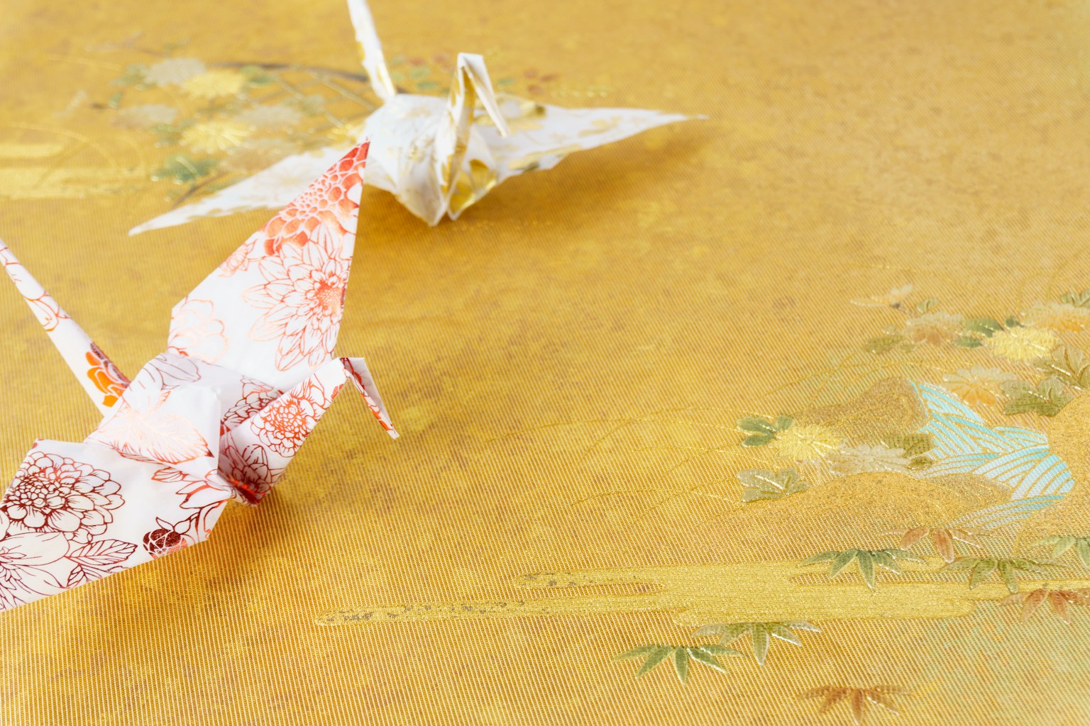 Dua bangau origami di latar belakang emas