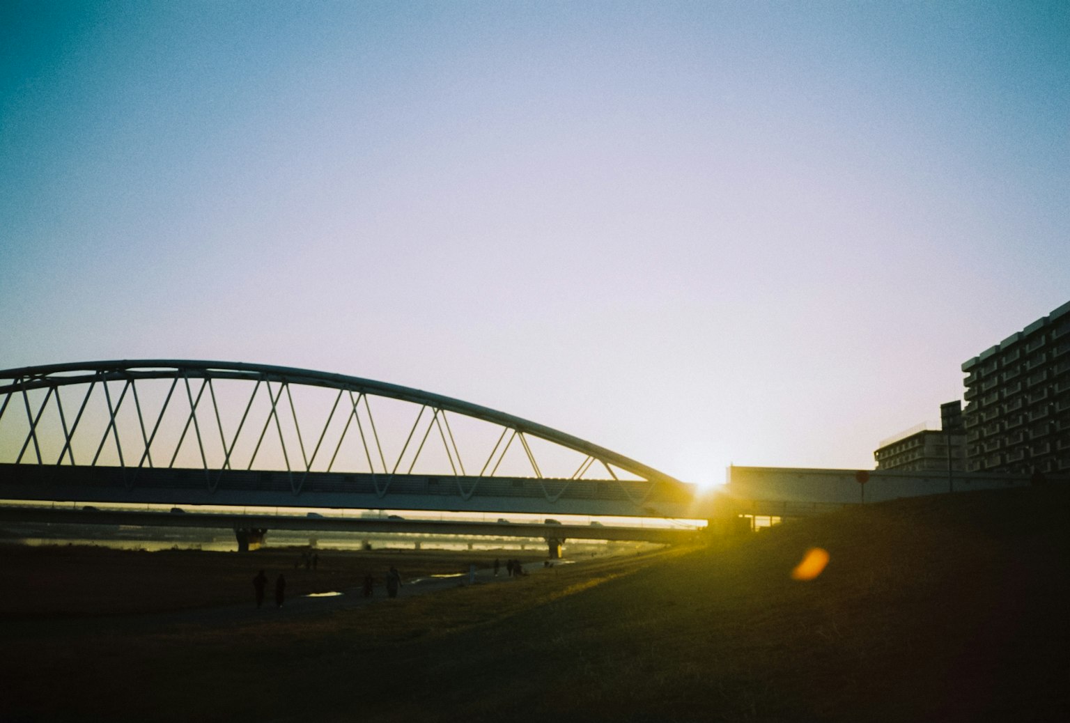 Silueta de un puente y un edificio iluminados por el atardecer