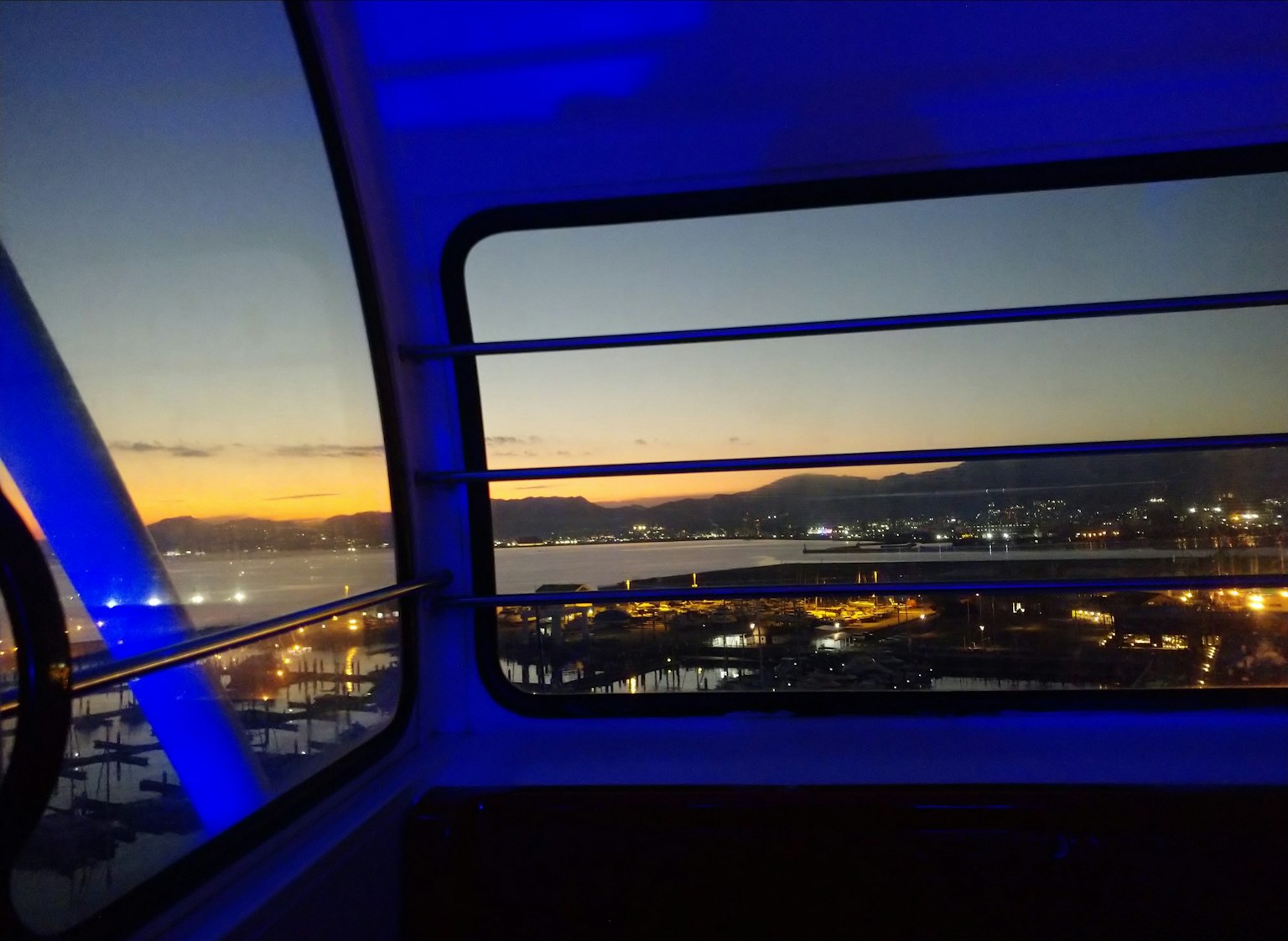 Vue depuis une capsule de grande roue au crépuscule montrant le port et un éclairage bleu