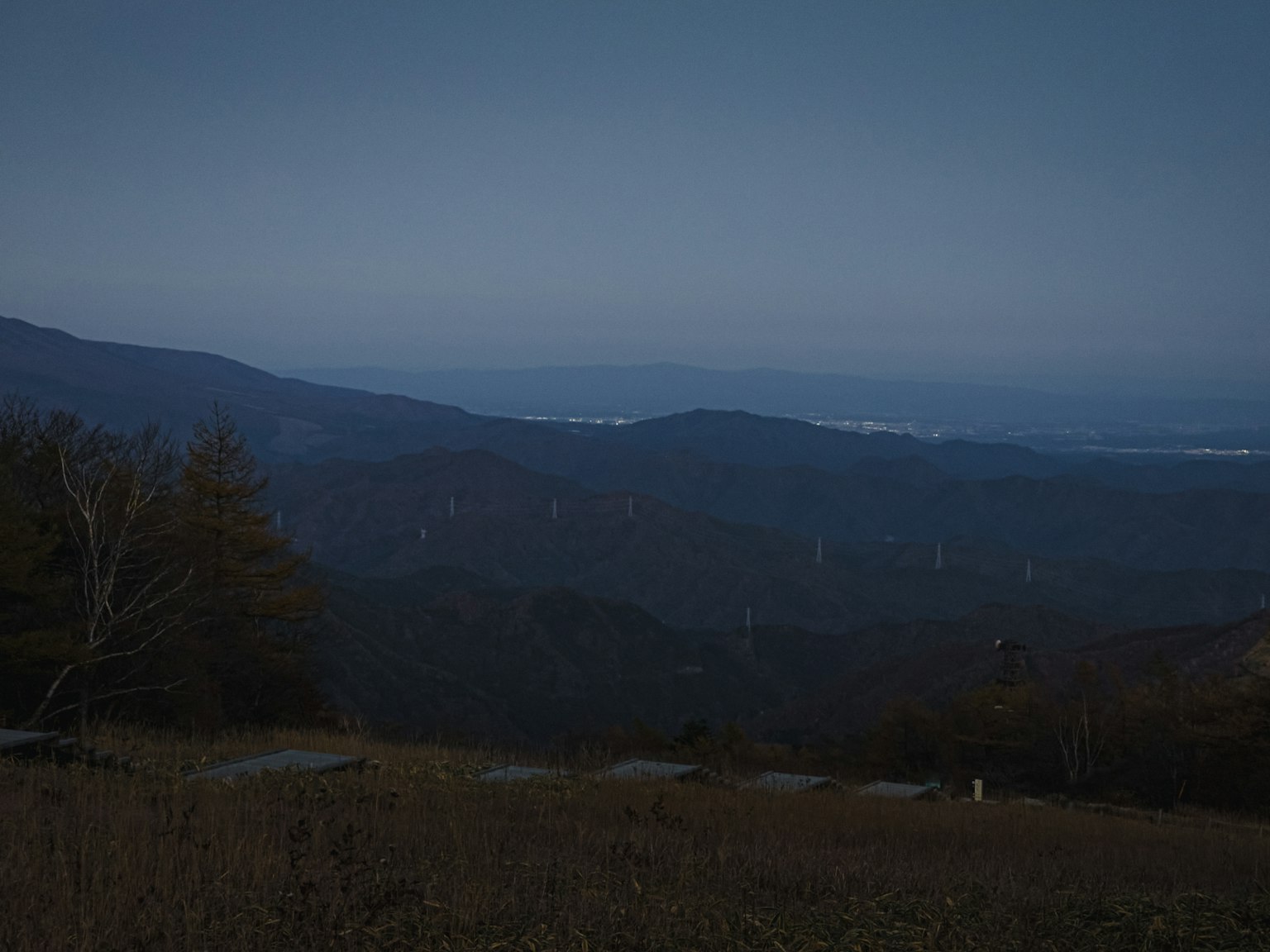 青い夕暮れの山岳風景と遠くの平野