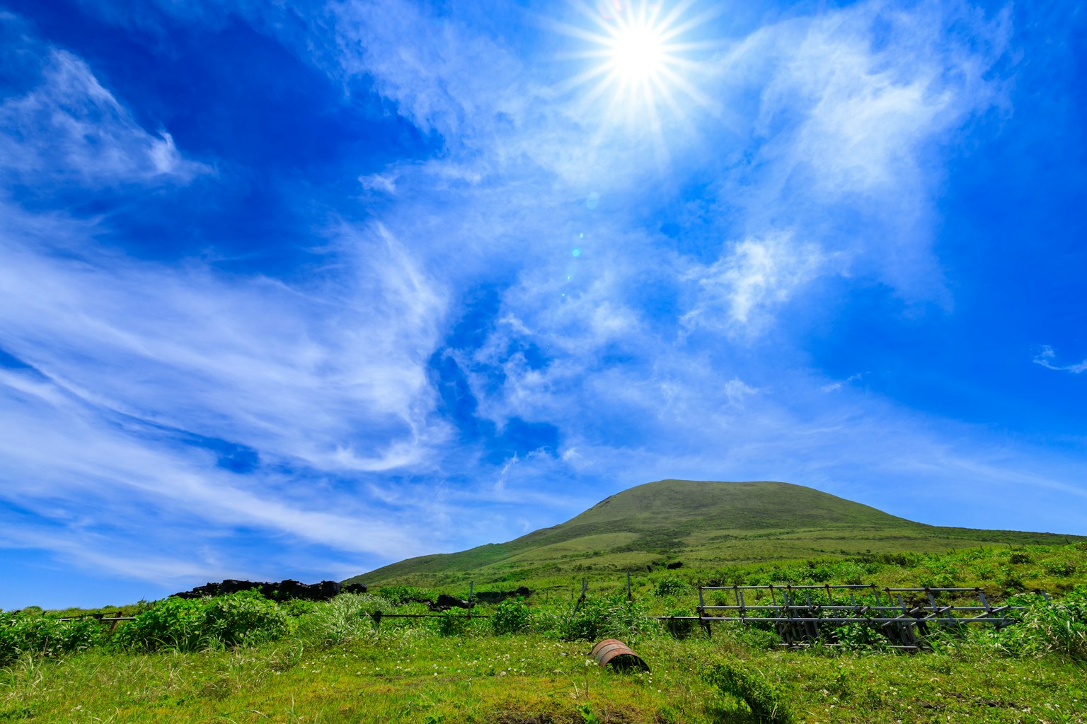 Collina verde sotto un cielo blu brillante e sole