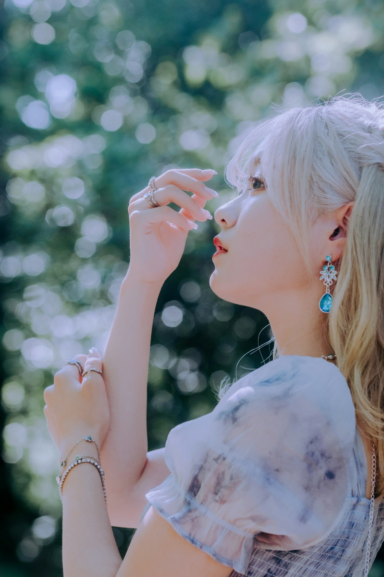 一位金髮女性在自然中擺姿勢背景模糊的綠色葉子