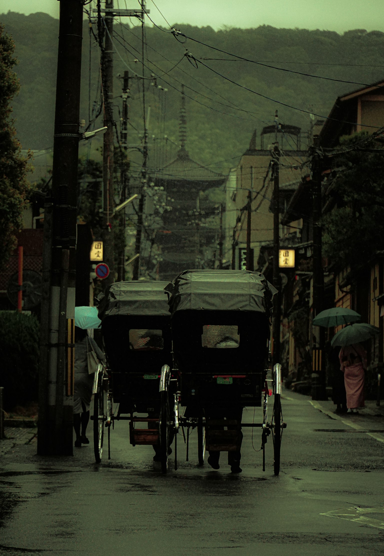 Rickshaws en una calle lluviosa con edificios tradicionales al fondo