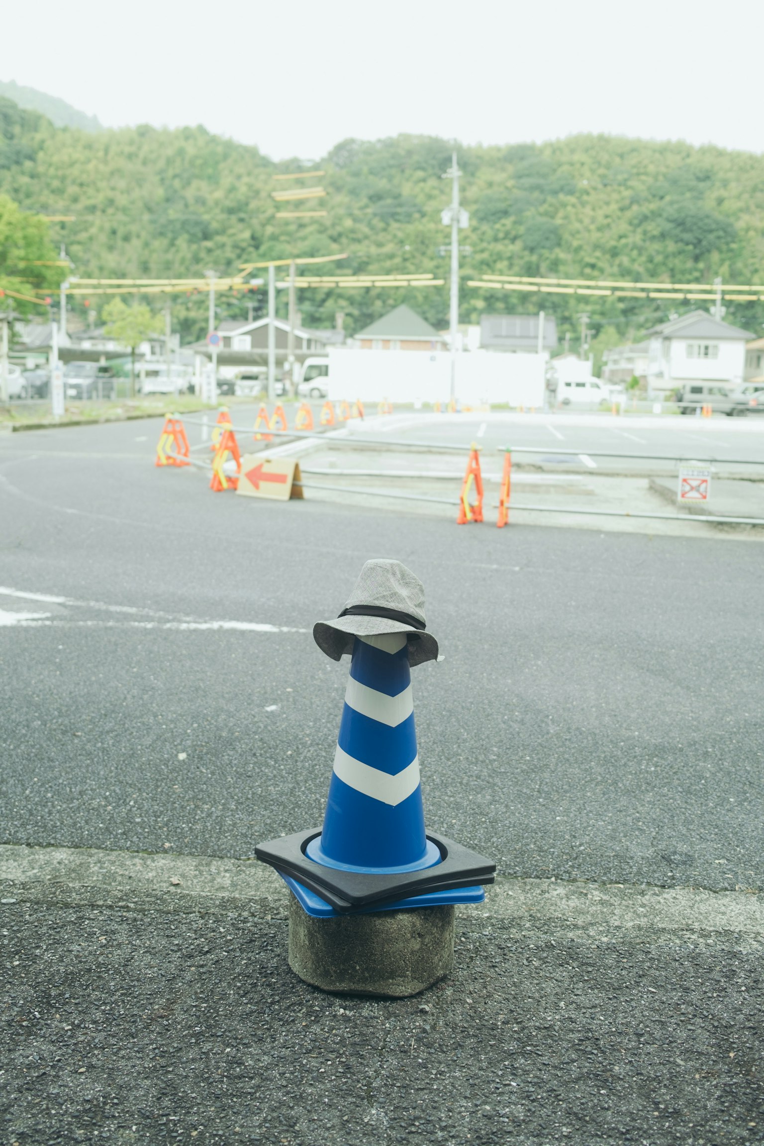 前景中有蓝白相间的交通锥，背景是绿色的山丘