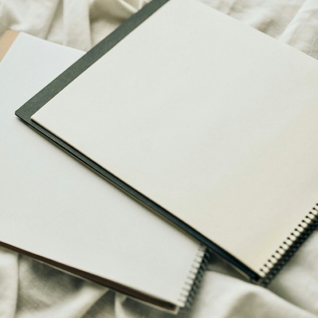 notebook and spiral-bound journal on a bed