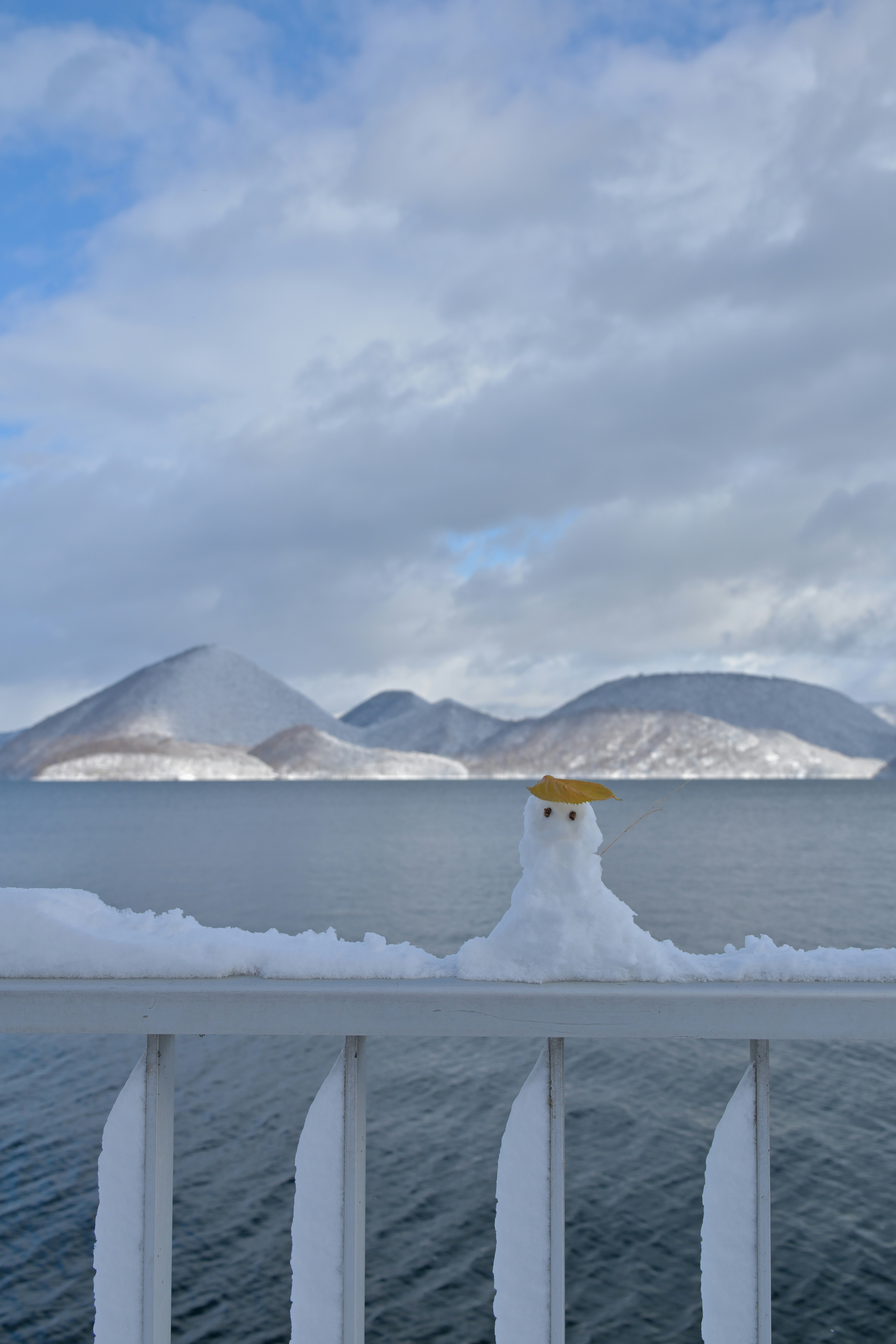 洞爺湖畔の海辺で雪だるまが柵の上に立つ景色
