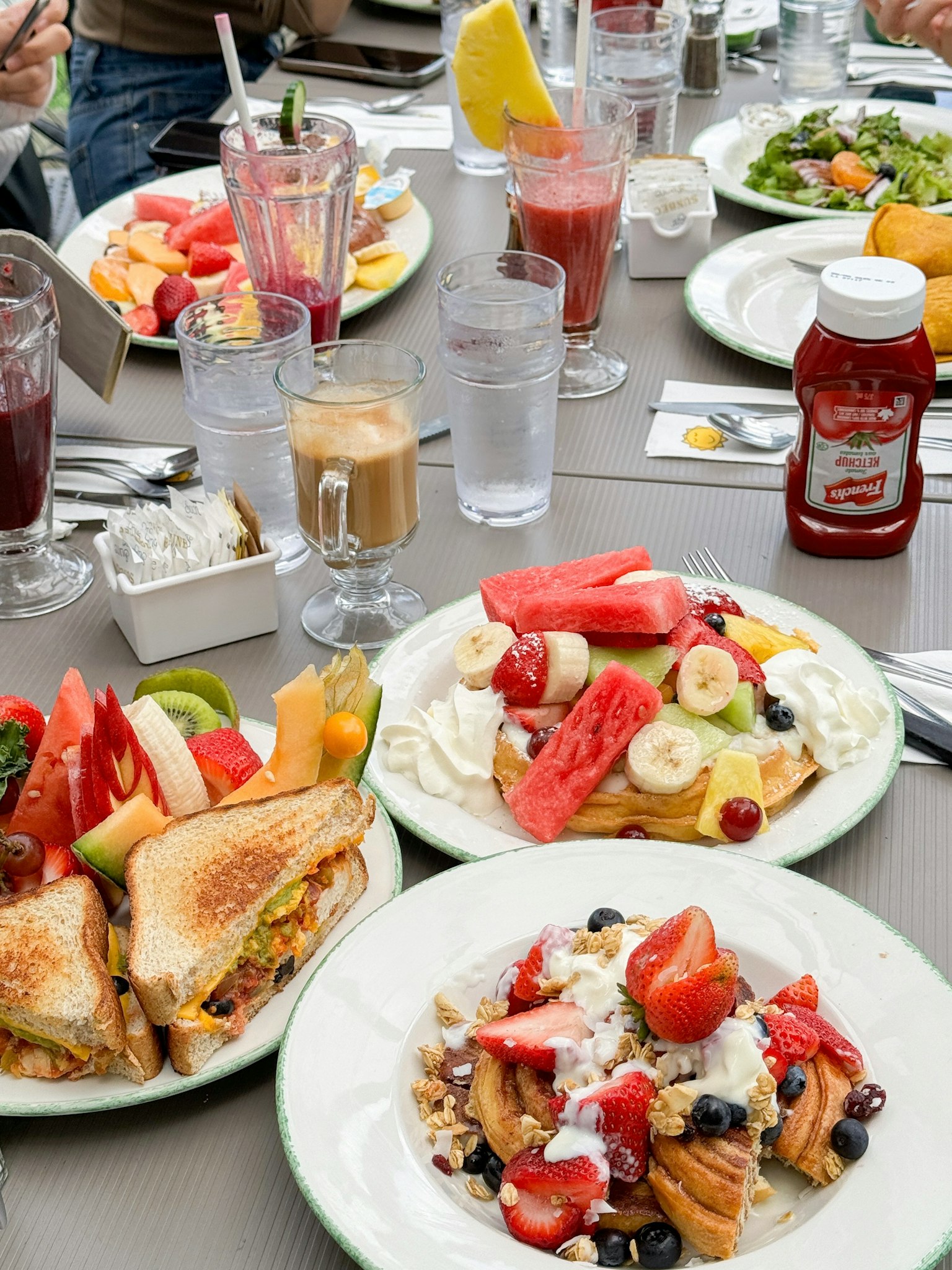 Une table de petit-déjeuner remplie de fruits colorés et de sandwichs
