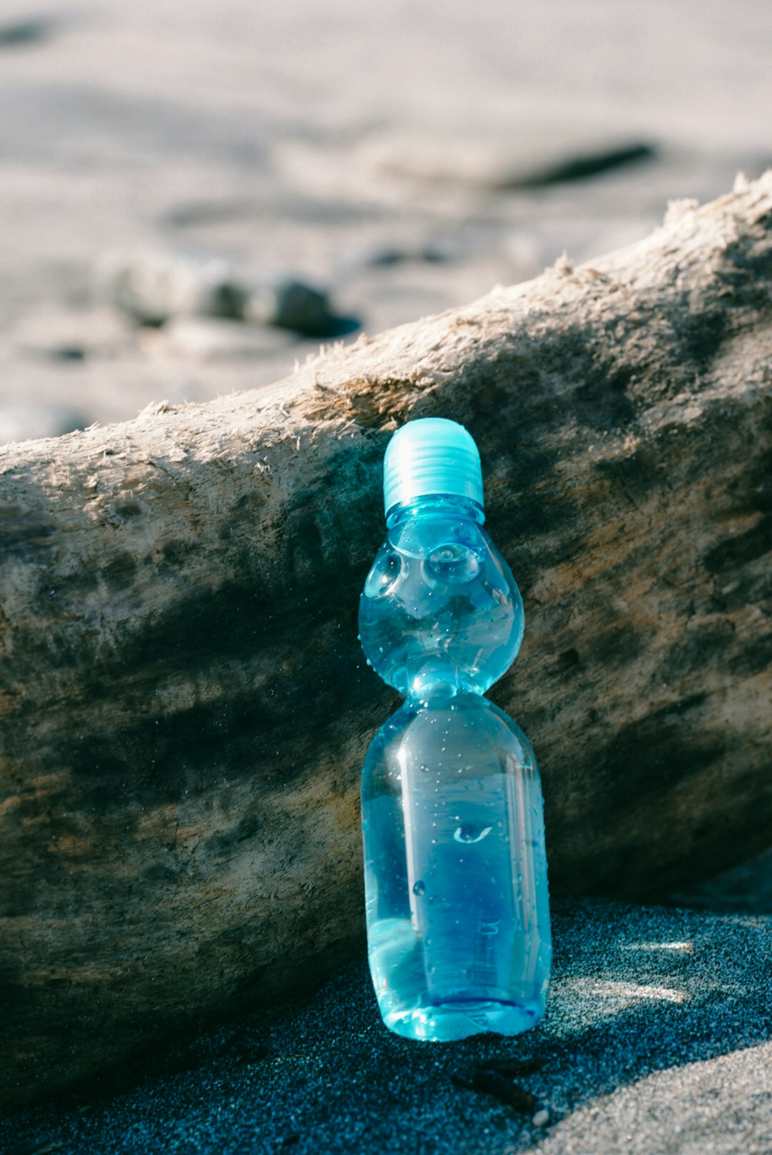 Sebuah botol minuman biru berdiri di dekat kayu