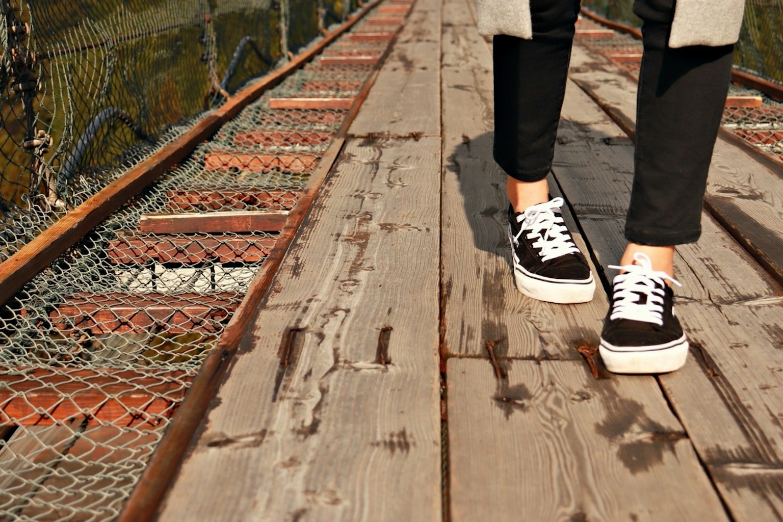 Pieds en sneakers marchant sur un pont en bois
