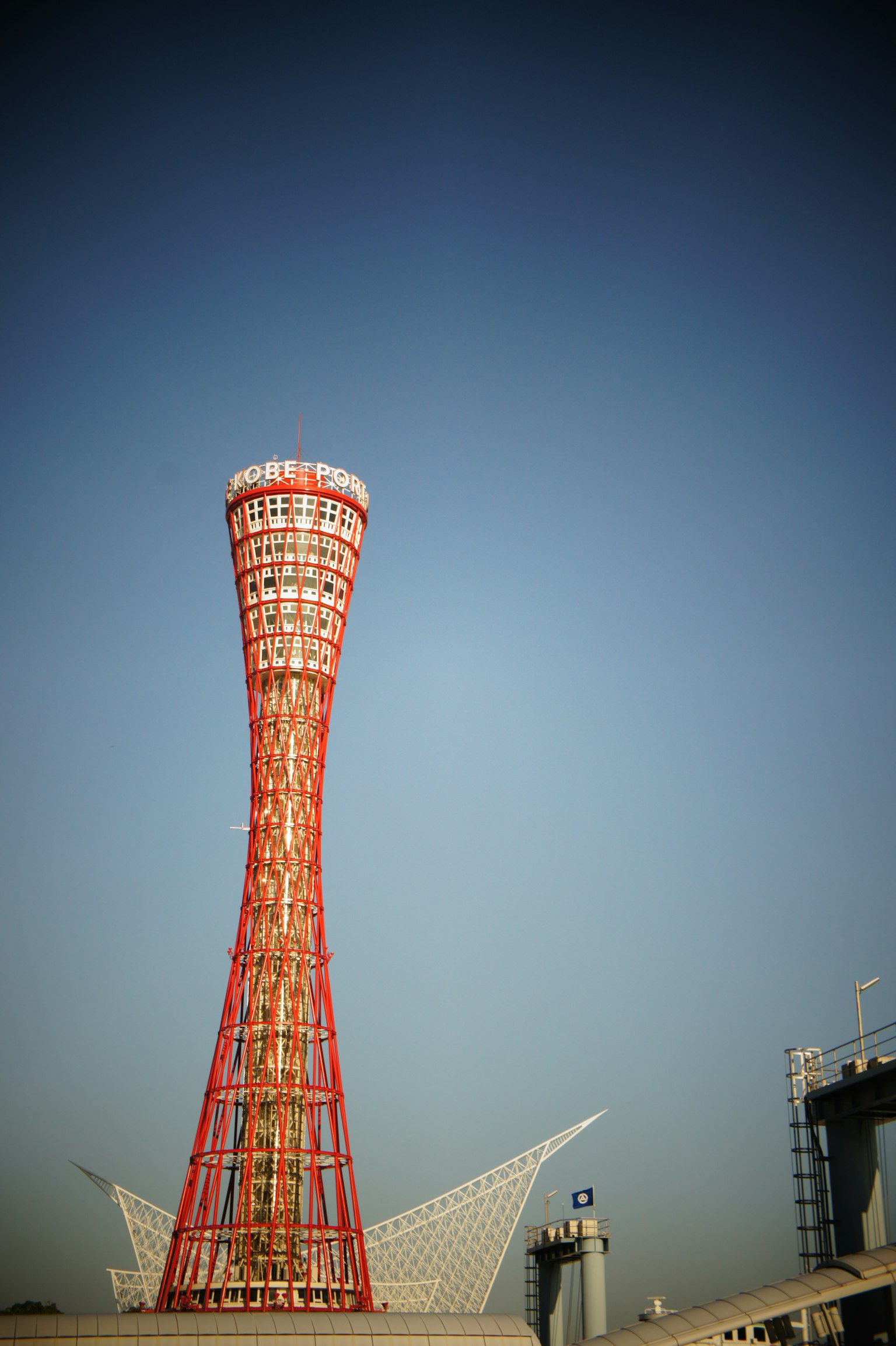 Torre del porto di Kobe con il suo design rosso distintivo contro un cielo blu chiaro