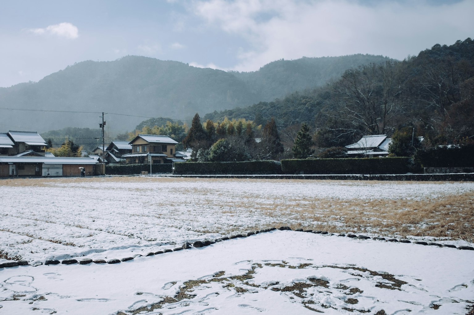 Campo di riso coperto di neve con montagne sullo sfondo