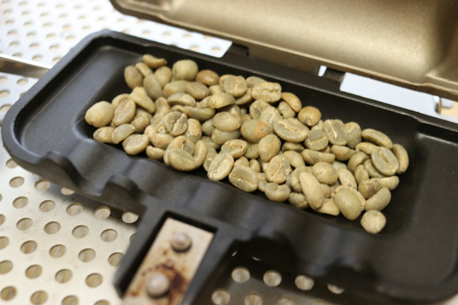 Rohe Kaffeebohnen in einem schwarzen Tablett angeordnet