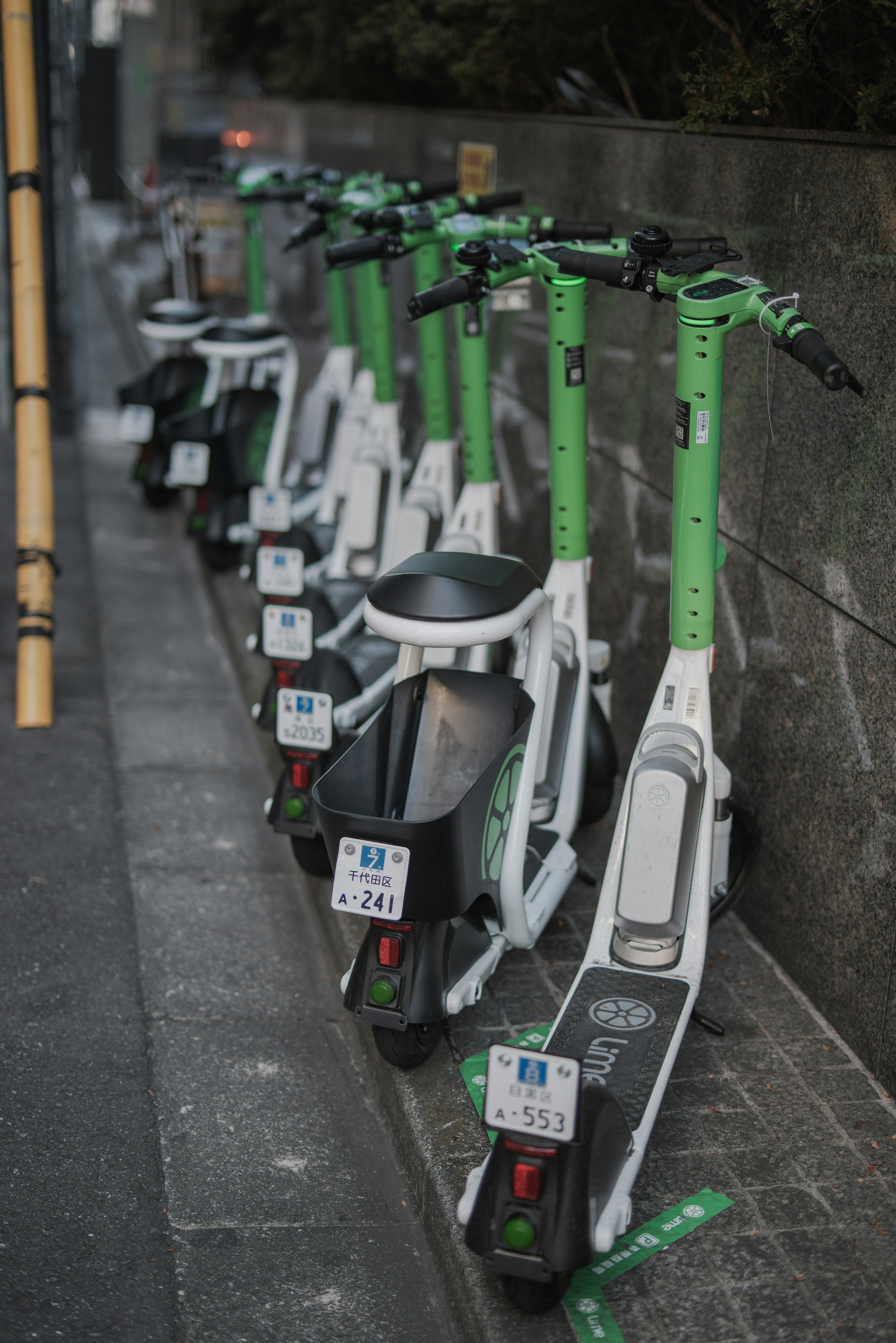 electric kick scooters lined up in an alley