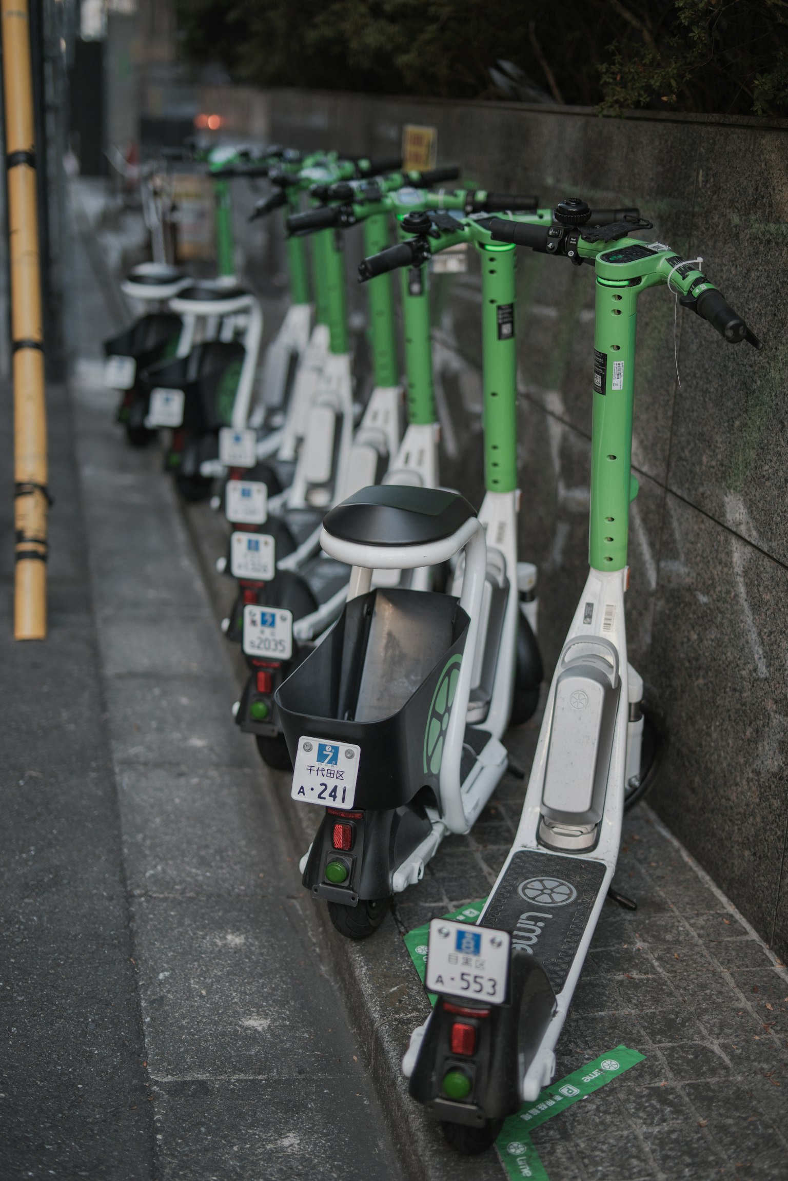 Rang de trottinettes électriques blanches avec des poignées vertes