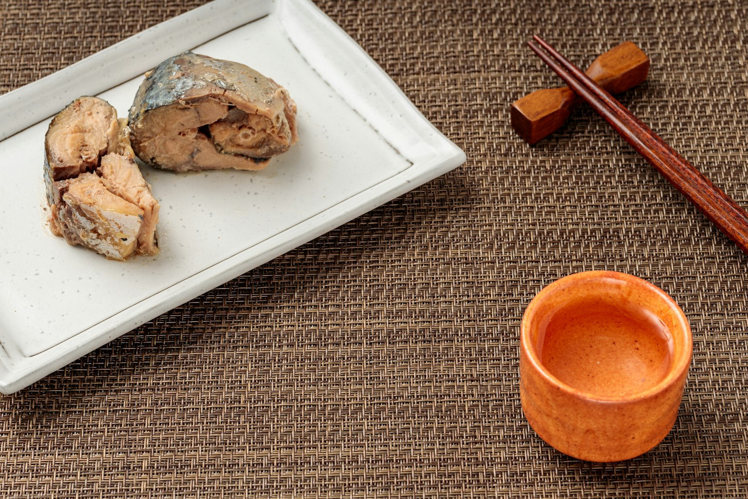 Fish pieces on a white plate with an orange cup nearby