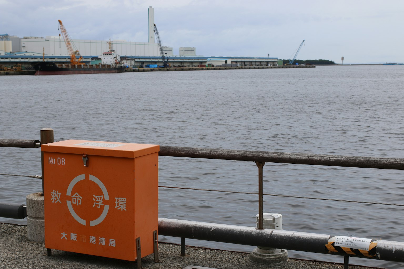 海滨的橙色垃圾箱和背景中的工业建筑