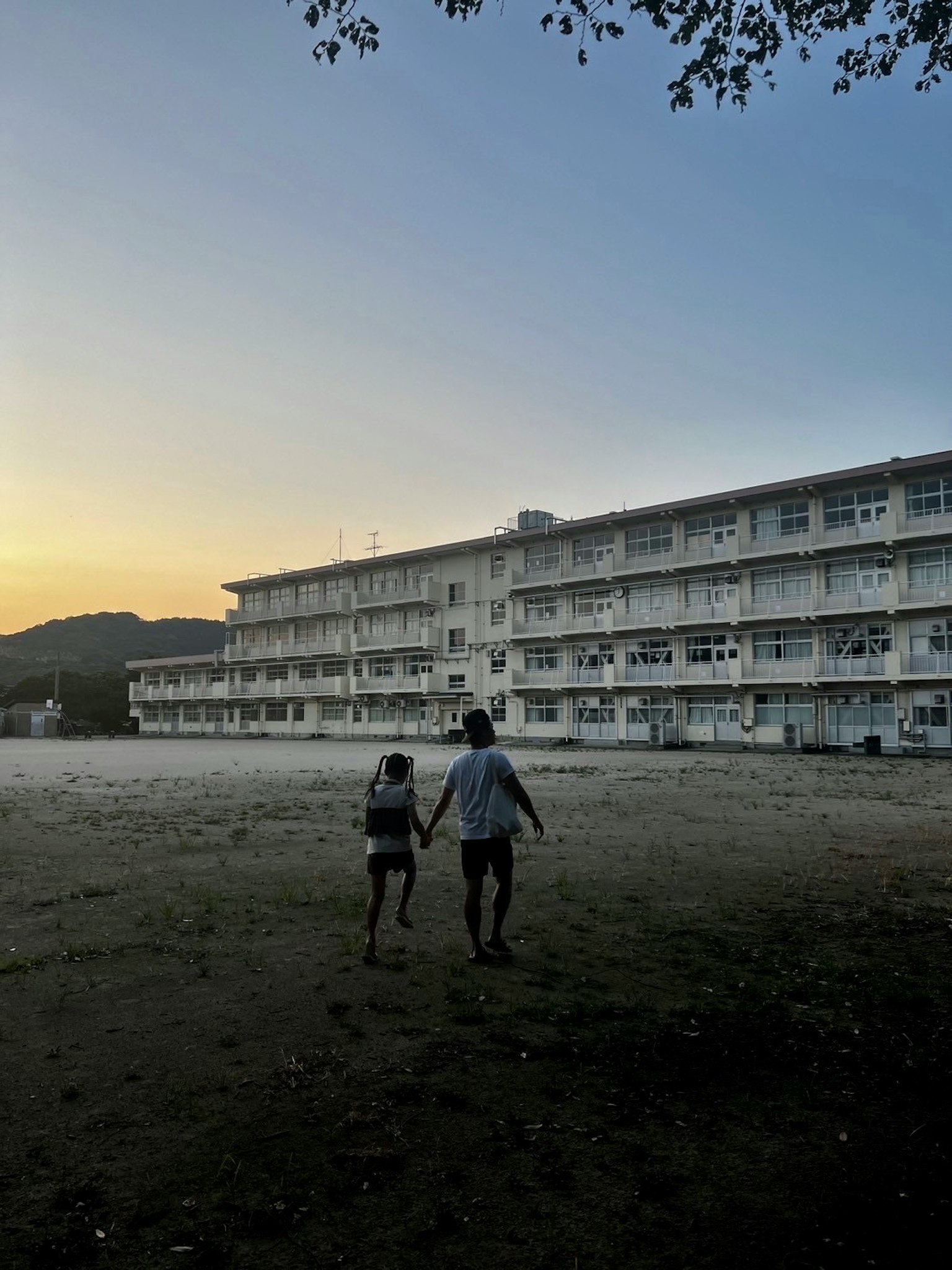 Due persone che si tengono per mano mentre camminano davanti a un vecchio edificio al tramonto