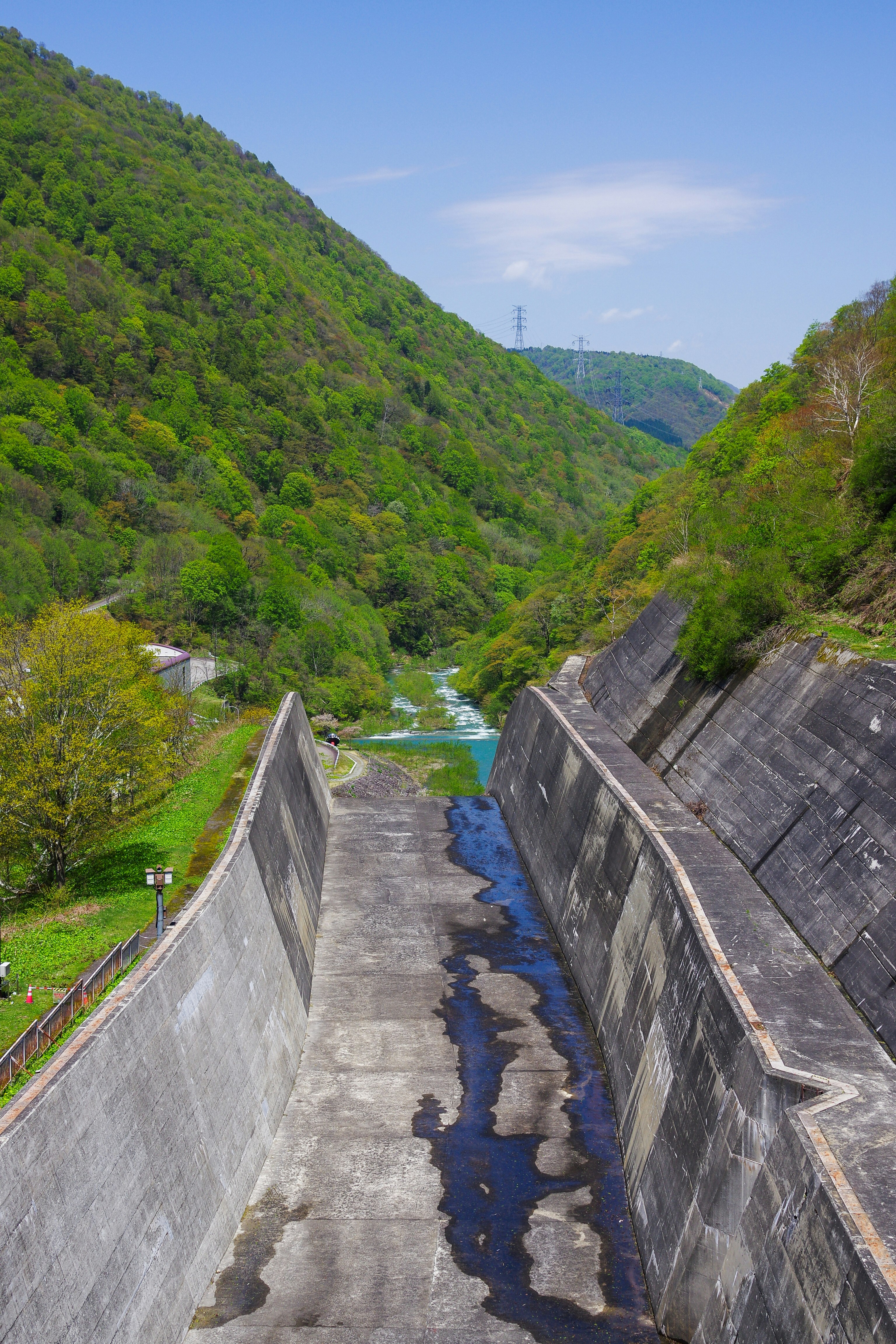 ダム堤体と水路が流れる発電所の景観