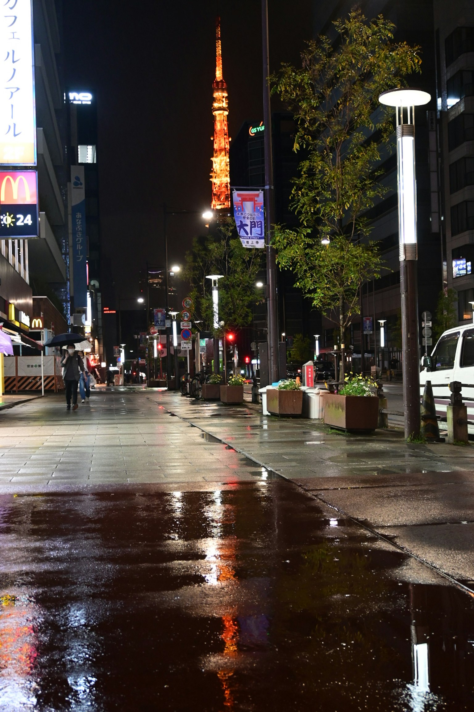 Pemandangan malam Menara Tokyo yang diterangi dengan pantulan di trotoar basah