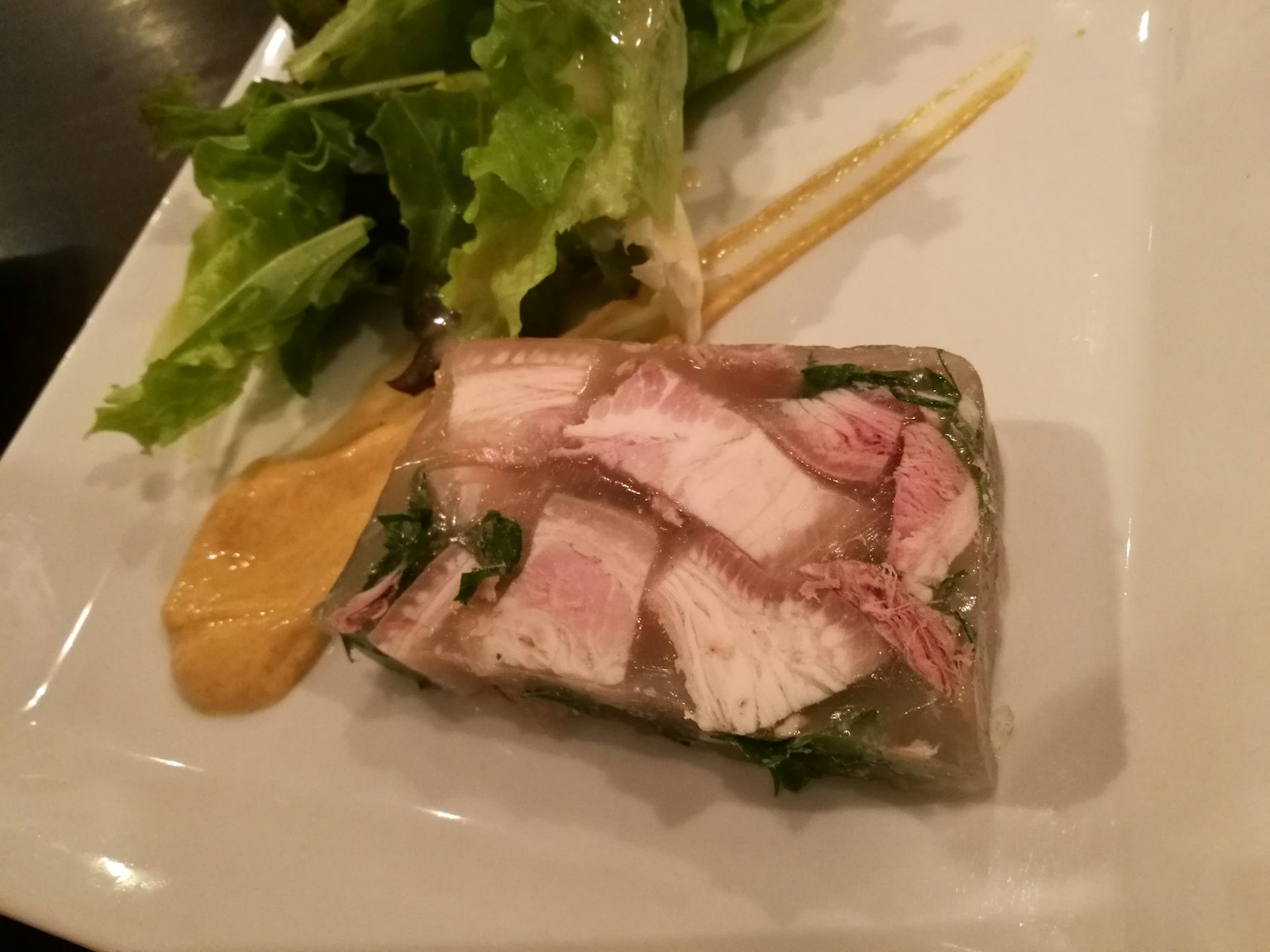 Terrina de carne envuelta en gelatina transparente acompañada de ensalada
