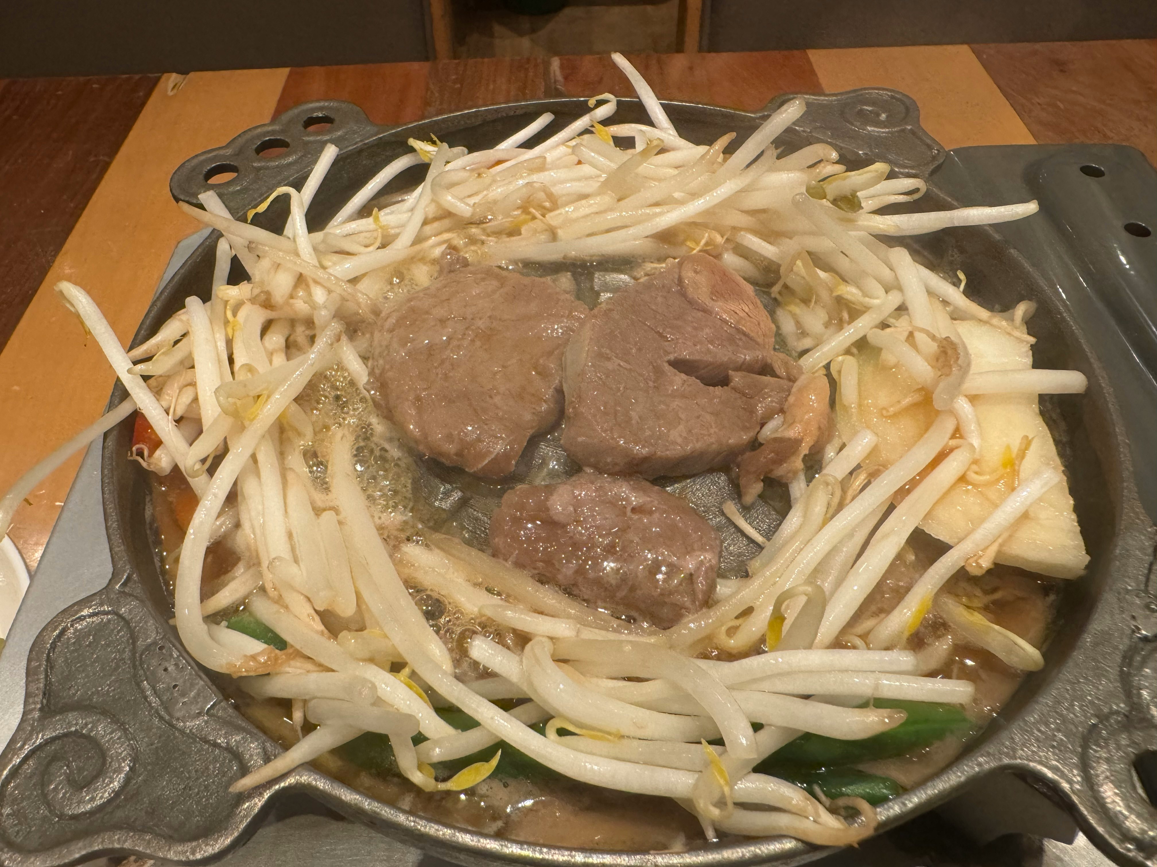 北海道ジンギスカンの焼き鍋で焼かれるラム肉と野菜の盛り合わせ