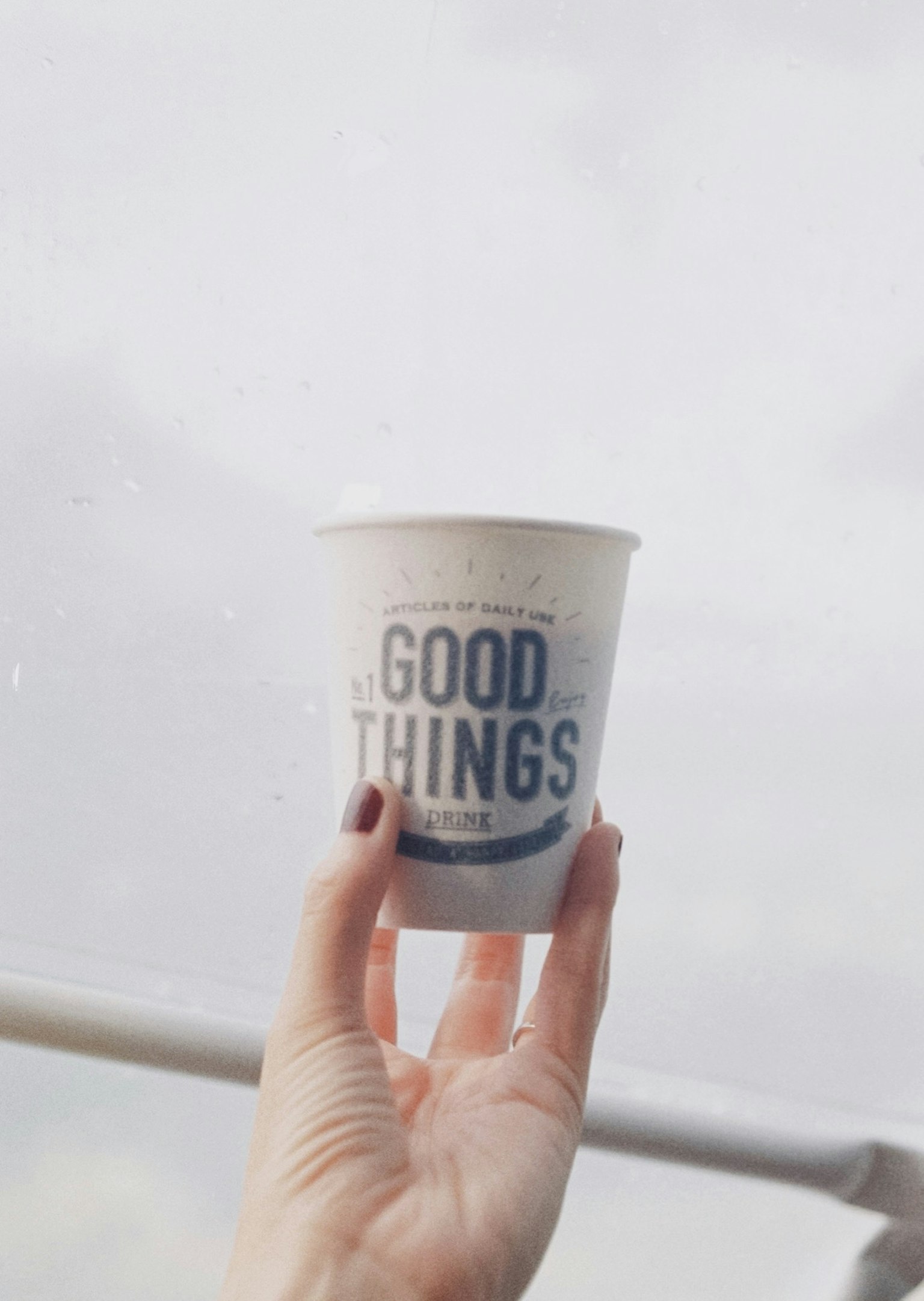 손에 들린 흰색 종이컵에 GOOD THINGS라는 글씨가 적혀 있다