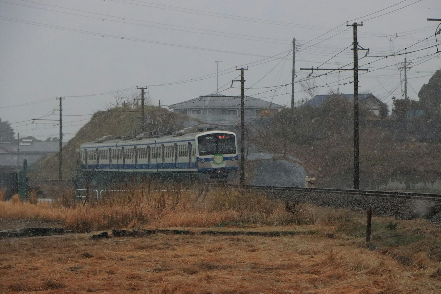 Kereta Jepang yang melintas di lanskap berkabut dengan saluran listrik