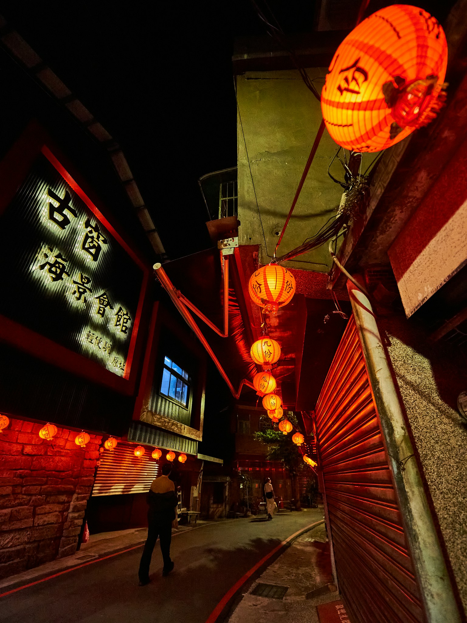 Narrow alley at night adorned with red lanterns and illuminated signs