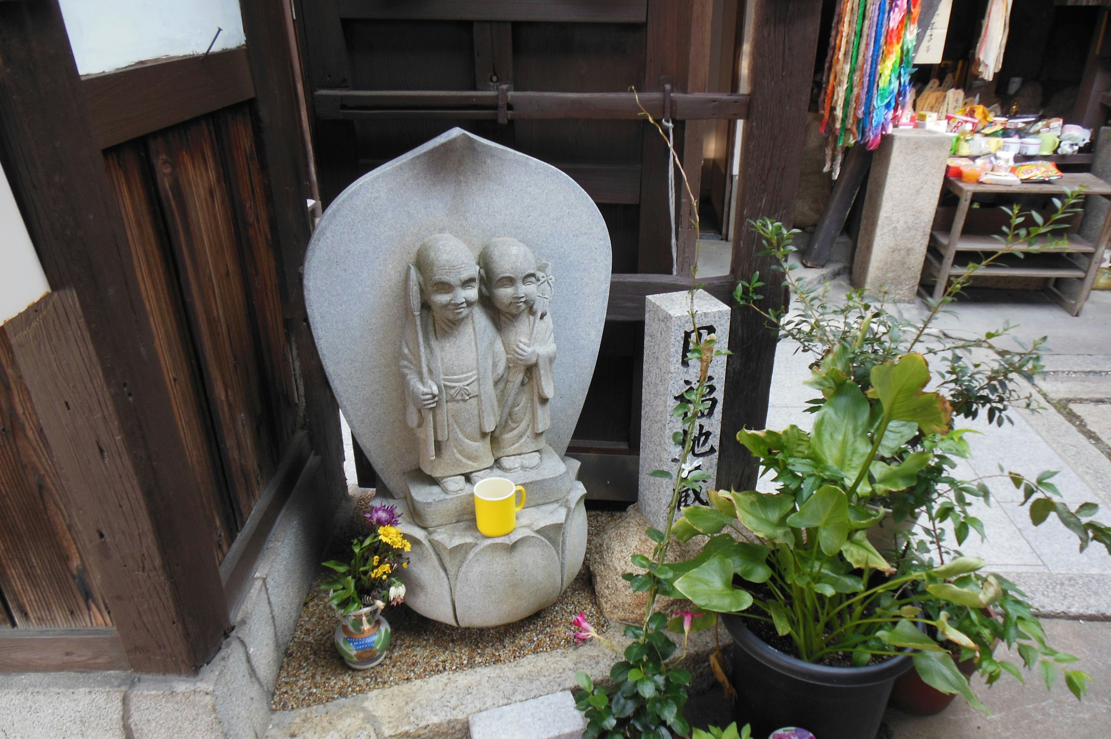 路边小型供奉摆设：石像与鲜花供品