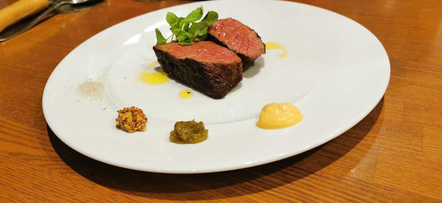 Saftiges Steak auf einem weißen Teller mit Beilagen und Saucen serviert