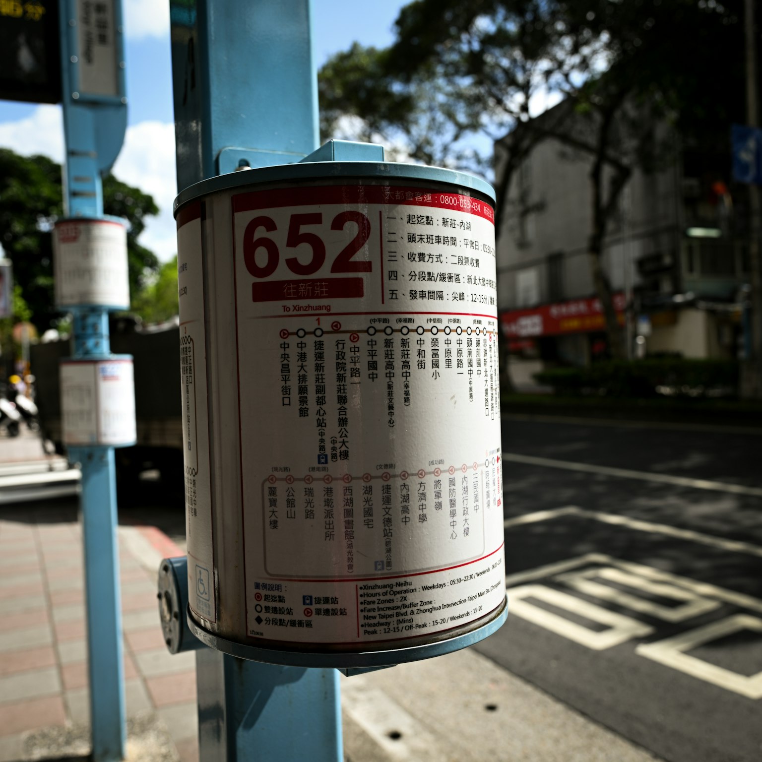 Panneau d'arrêt de bus affichant l'horaire sur un poteau bleu