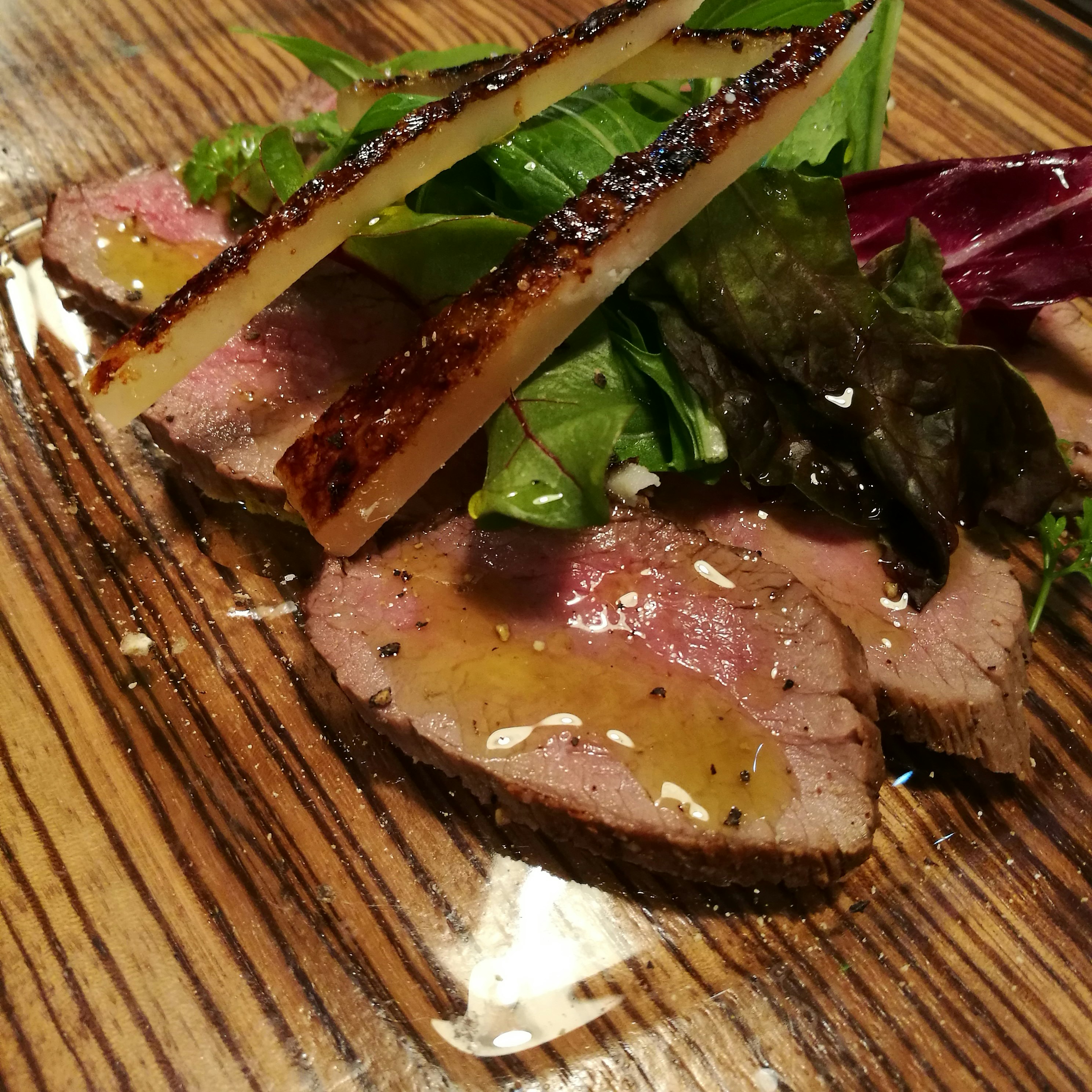 roasted meat with salad on a wooden cutting board