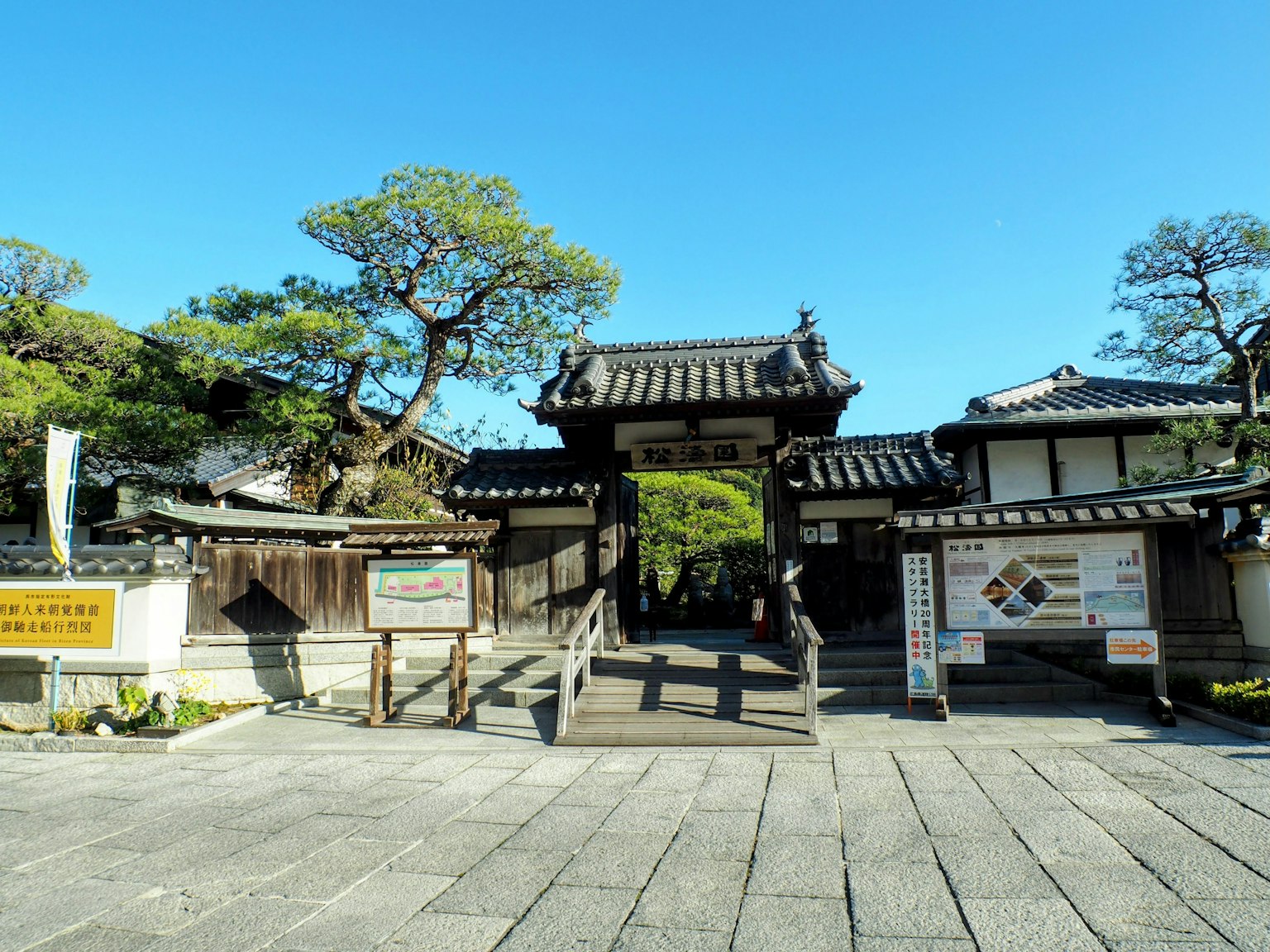 Traditionelles japanisches Tor mit umliegendem Grün unter klarem blauen Himmel