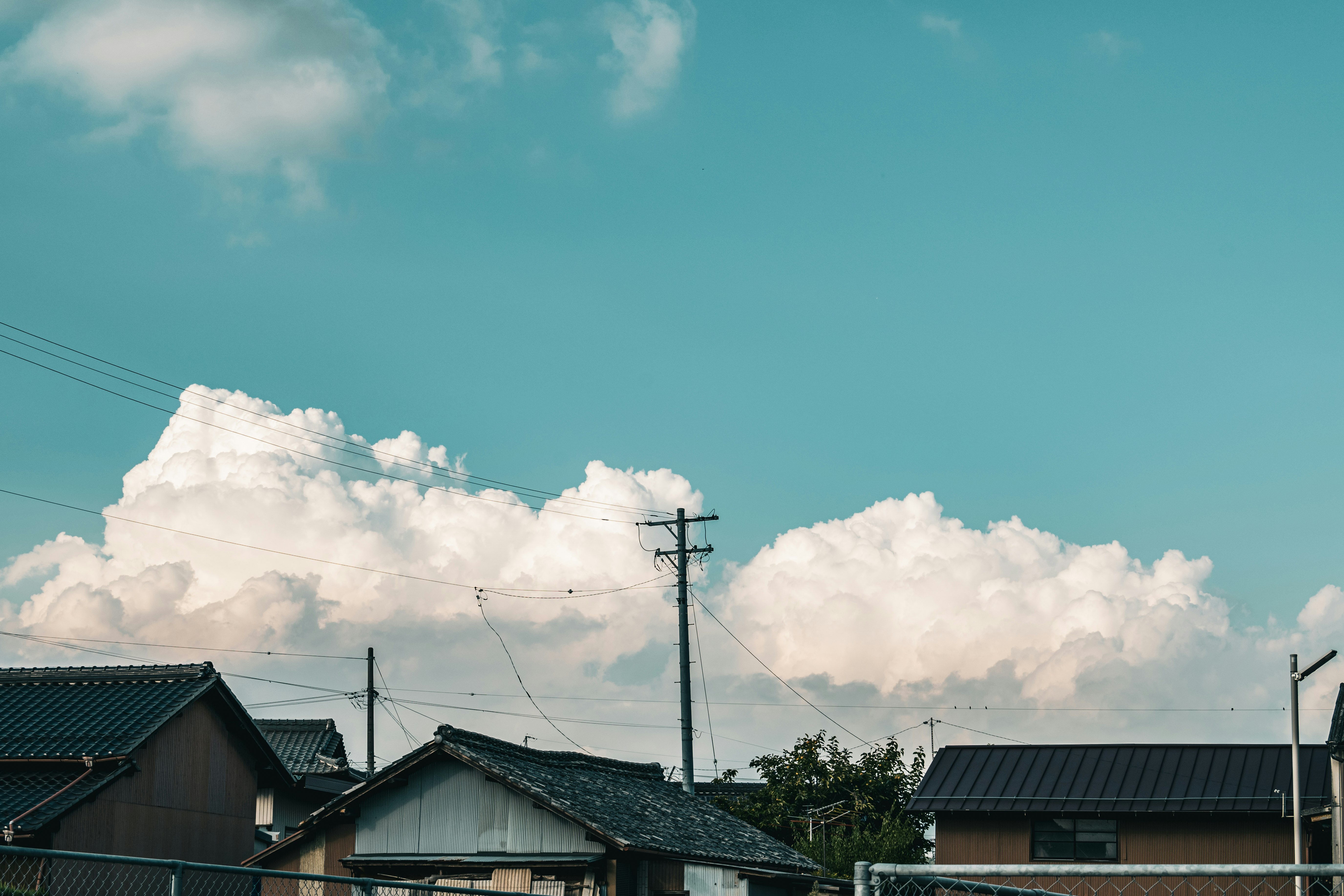 青空の下、屋根が並ぶ住宅街の空
