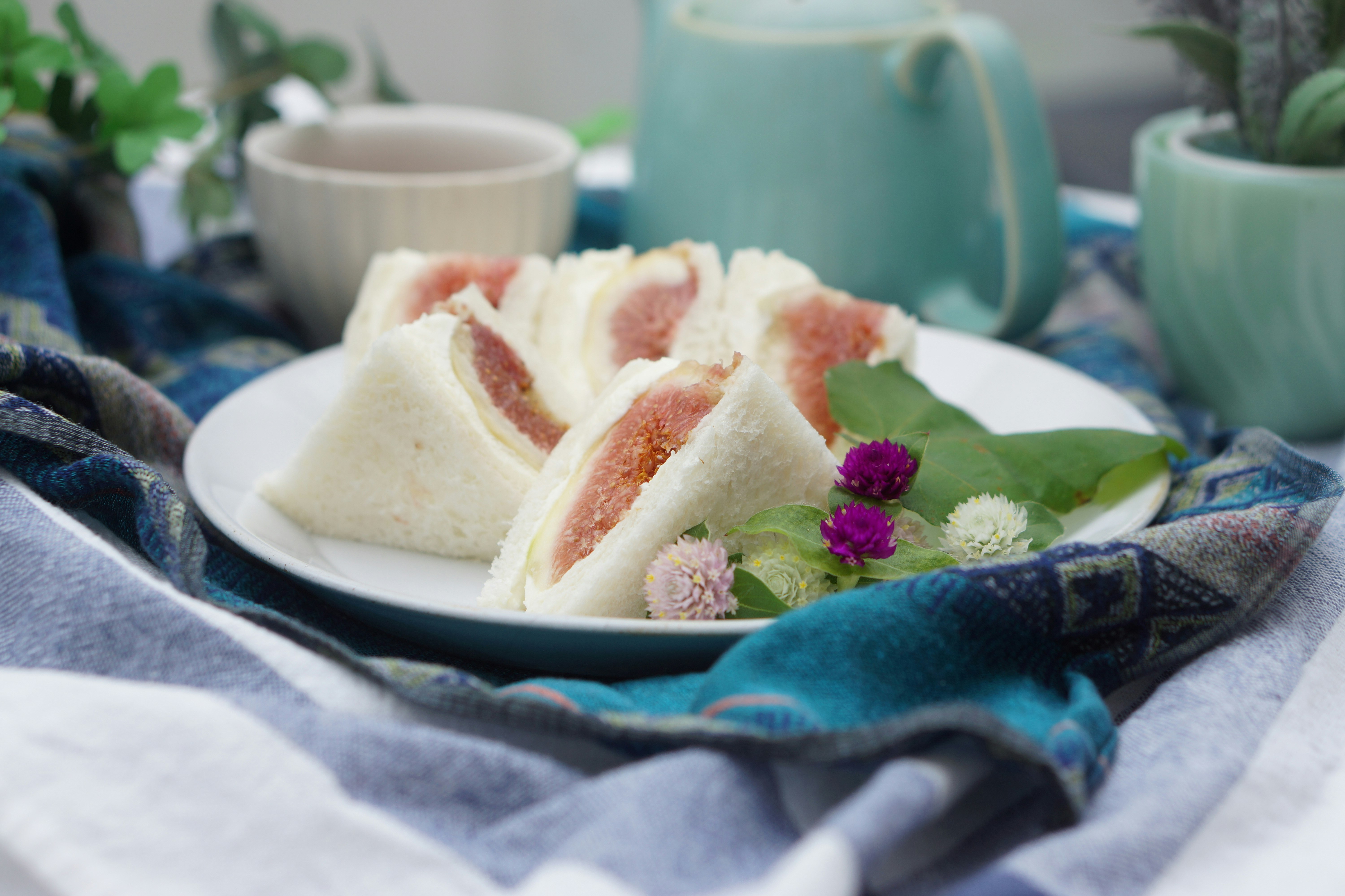 Sándwiches sobre una mesa con guarnición floral sobre una tela azul